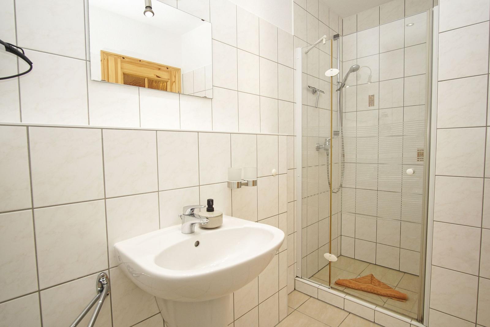 Badezimmer mit Dusche, Waschbecken und Spiegel