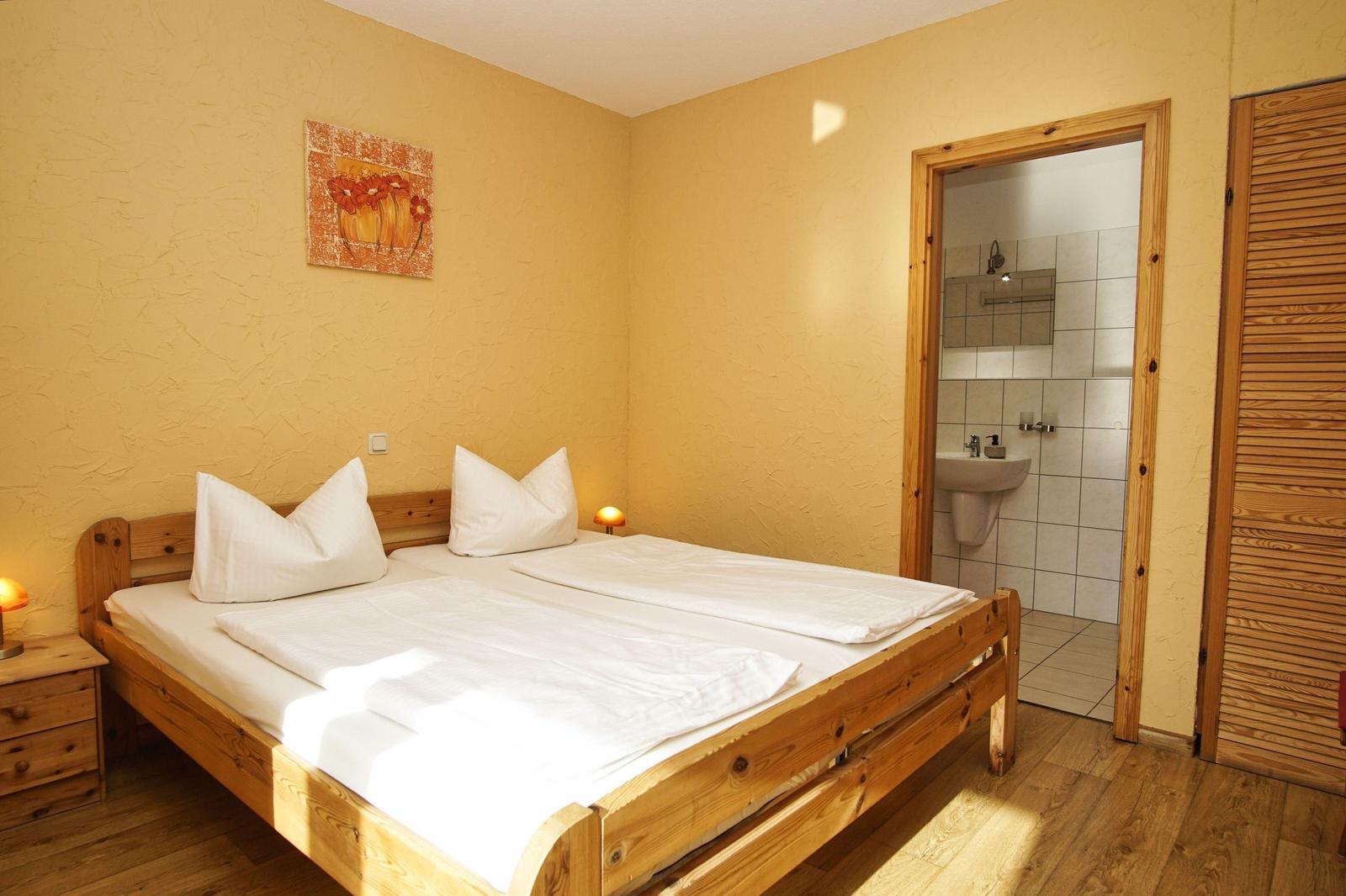 Zimmer mit Holzbett, Wandbild und Blick in Bad