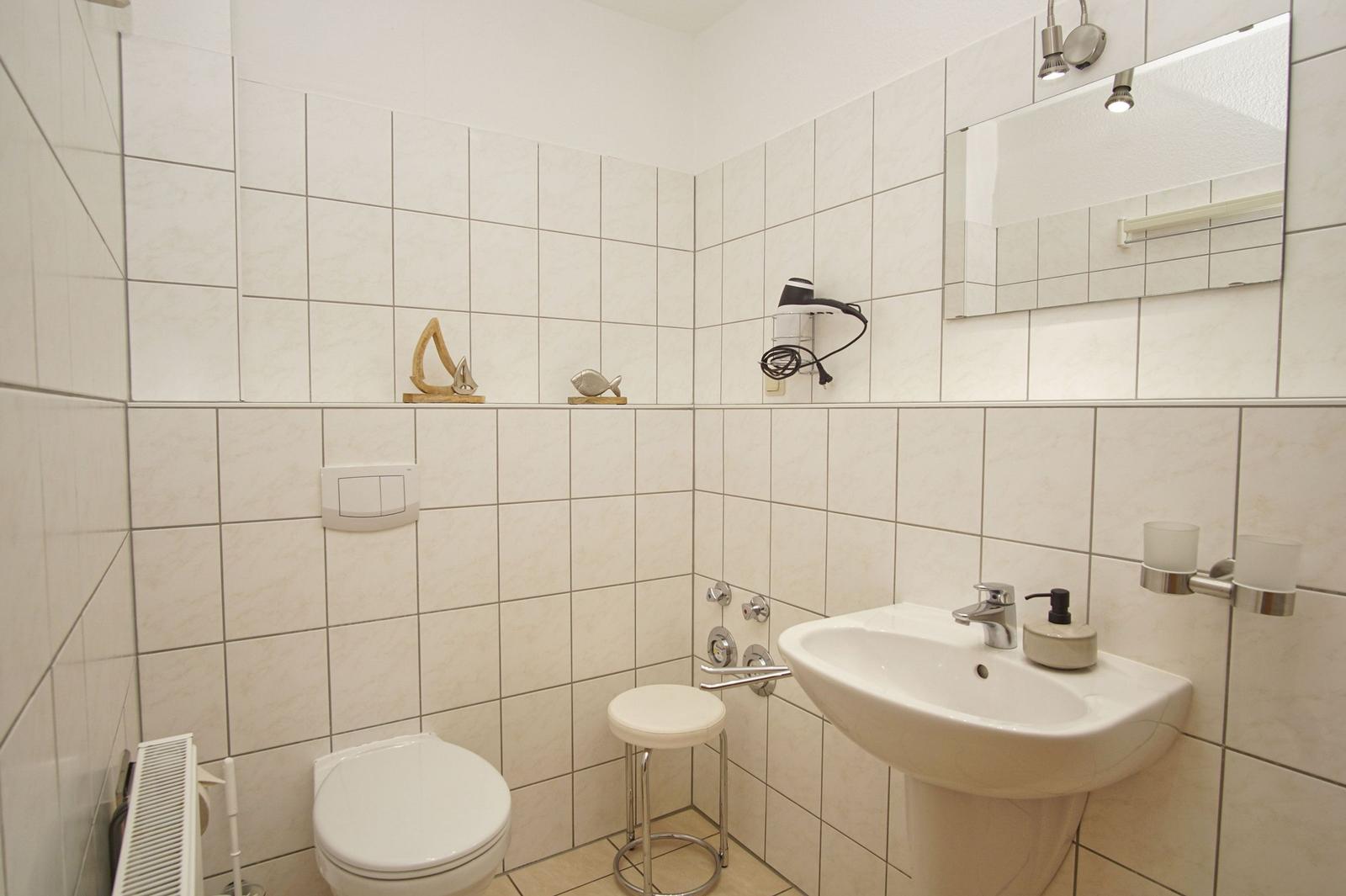 Badezimmer mit Toilette, Waschbecken und Spiegel an der Wand.