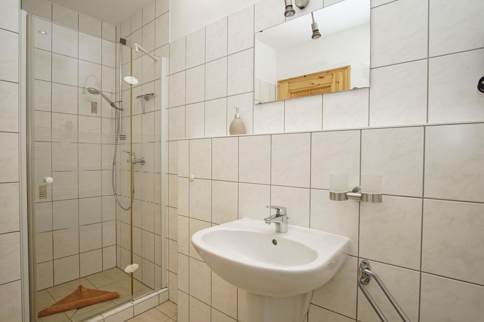 Badezimmer mit Dusche, Waschbecken und Spiegel