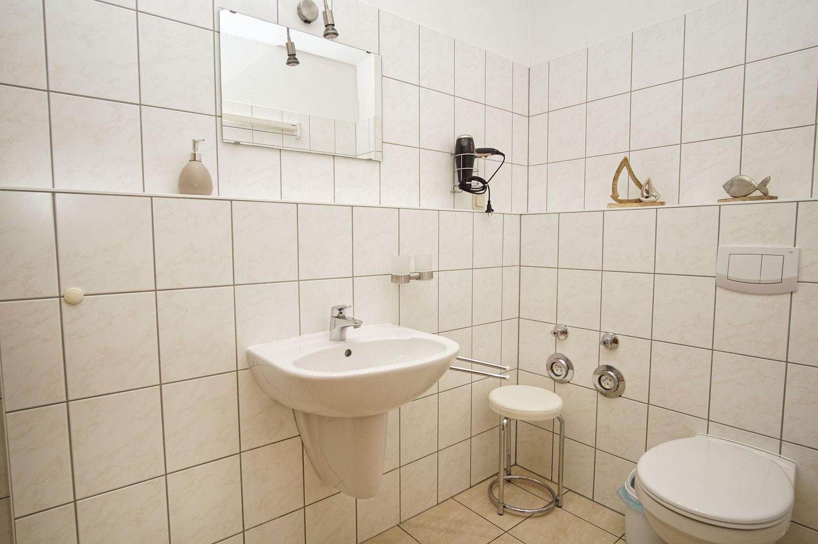 Badezimmer mit Waschbecken, Spiegel, Toilette und Dusche