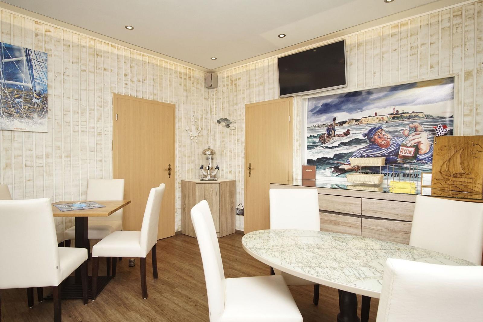 Esszimmer mit zwei Tischen, Wandbildern und Fernseher an der Wand.