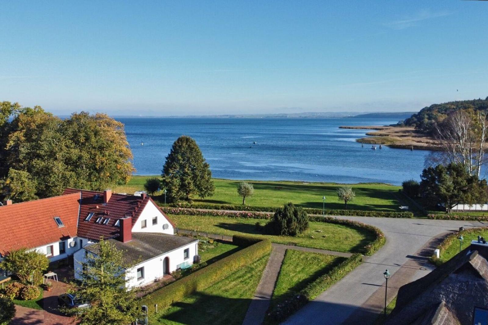 Haus mit rotem Dach, grüner Wiese und Blick auf See