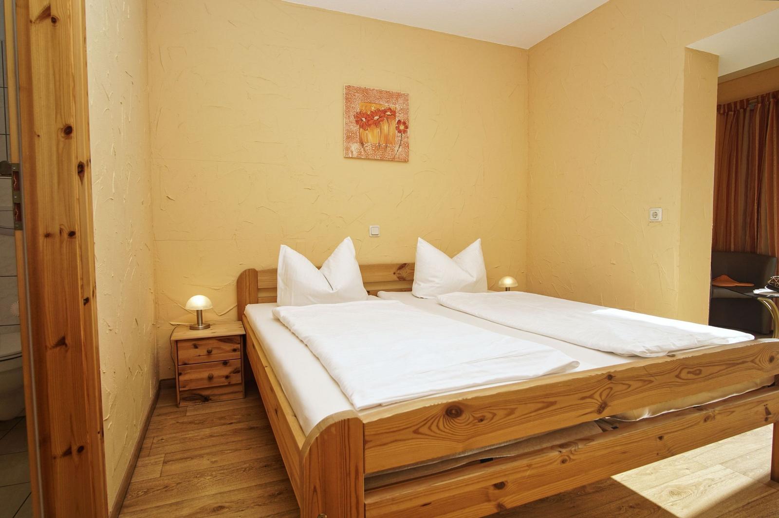 Schlafzimmer mit Holzbett, Nachttisch und Wandbild.