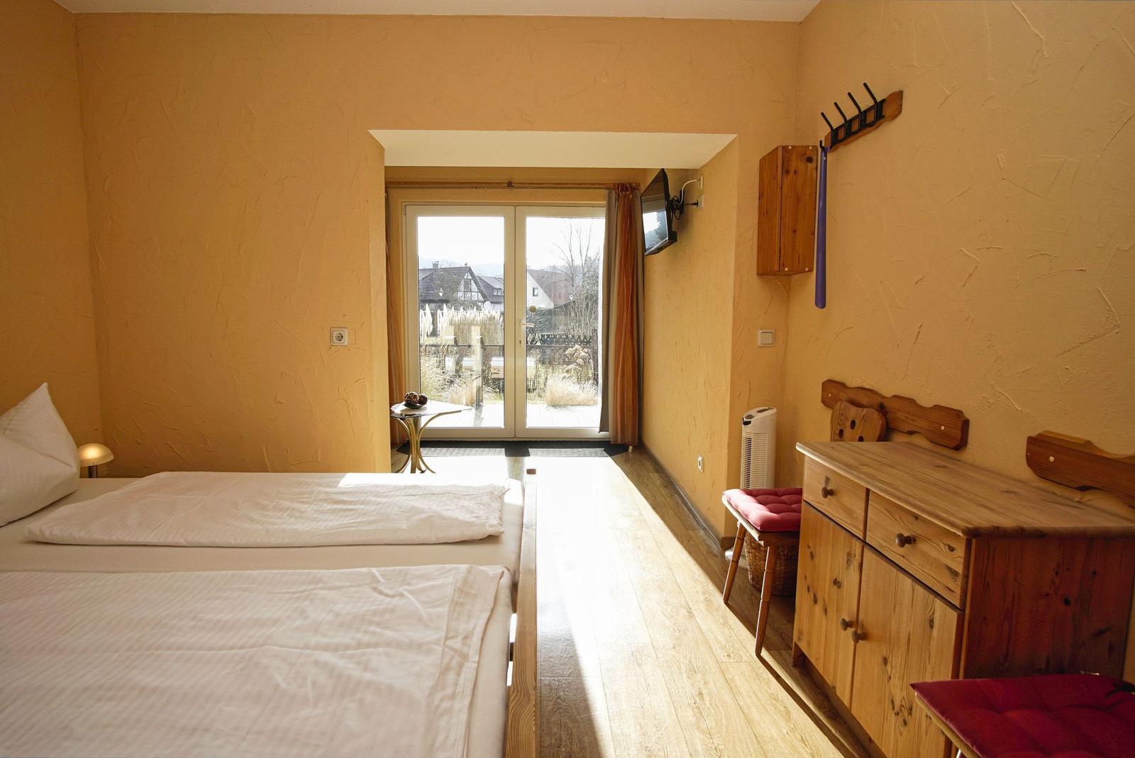 Zimmer mit Doppelbett, Holzmöbel und Balkonansicht