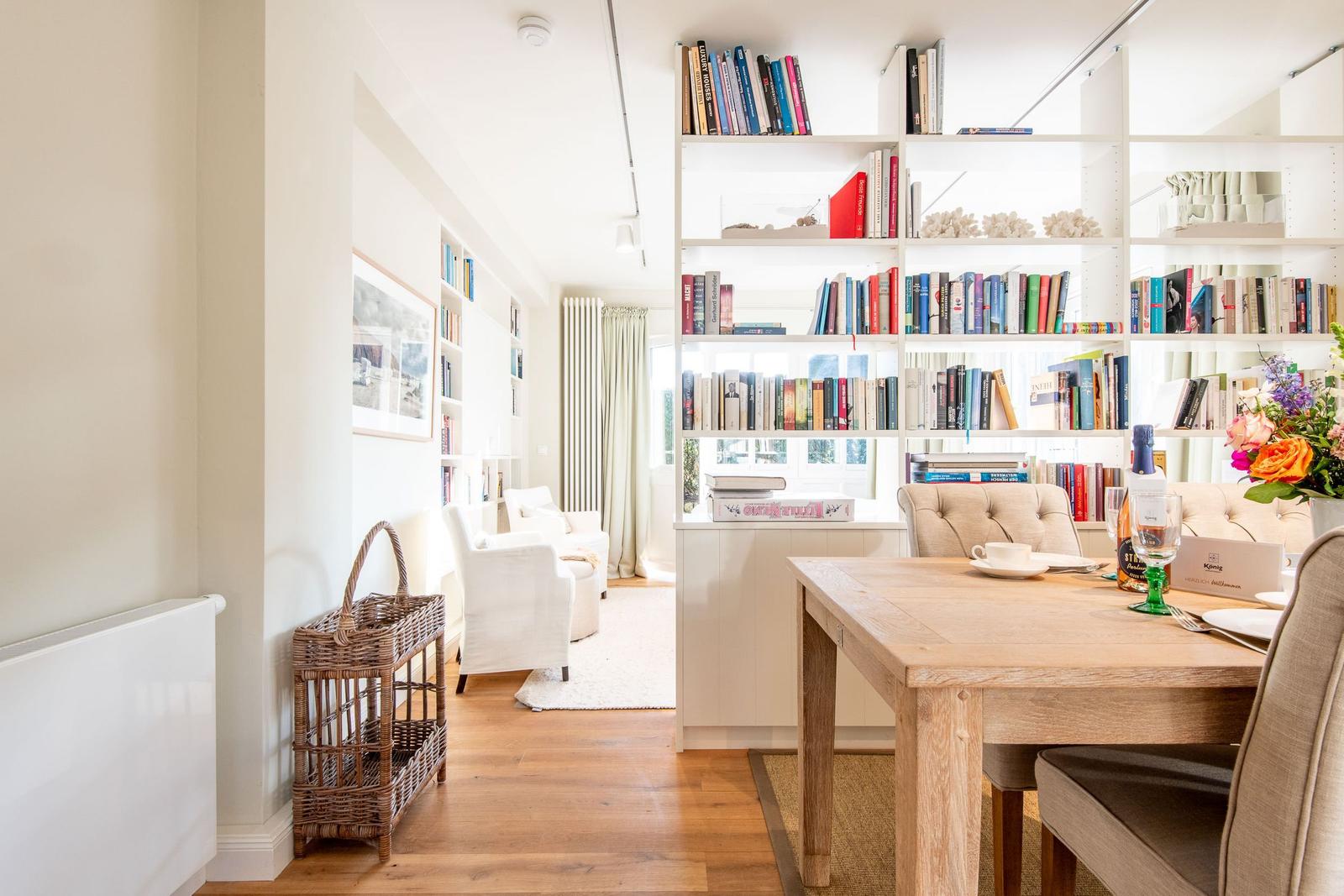 Essbereich mit Holztisch und Bücherregal im Hintergrund.