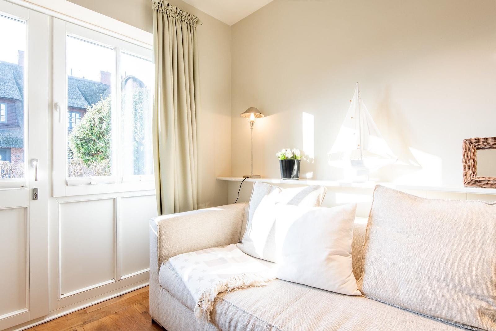 Ein Wohnzimmer mit Sofa, Fenster und Dekoration.