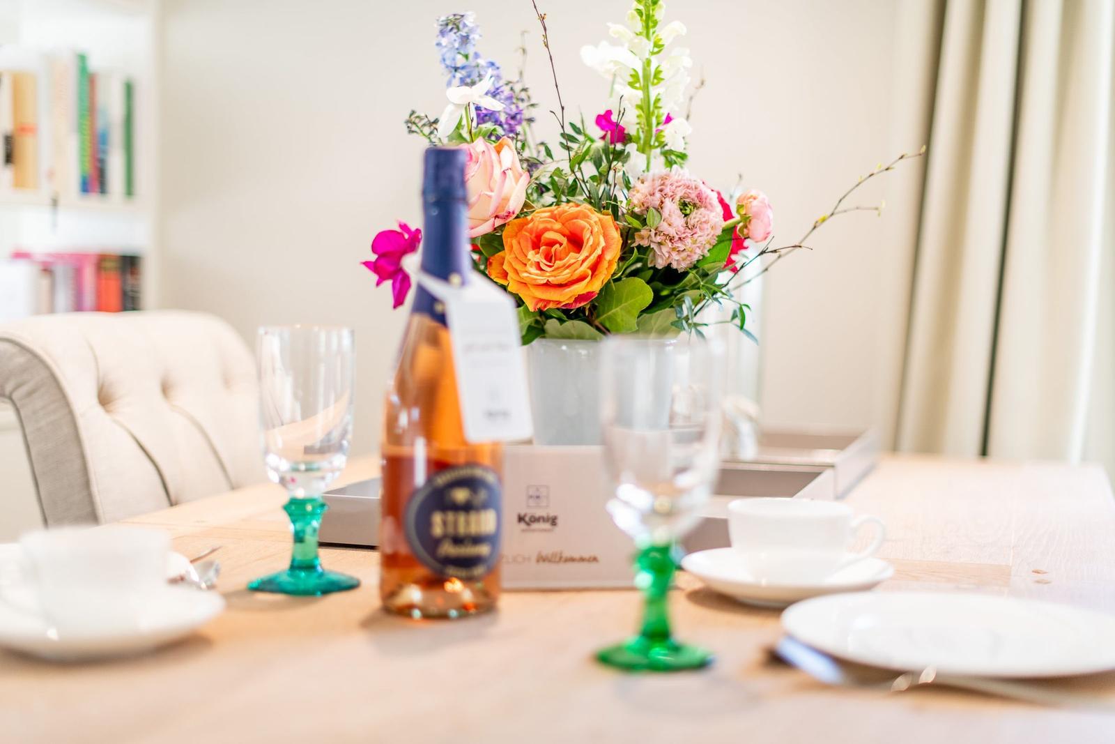 Tisch mit Blumen, Weinflasche und Geschirr