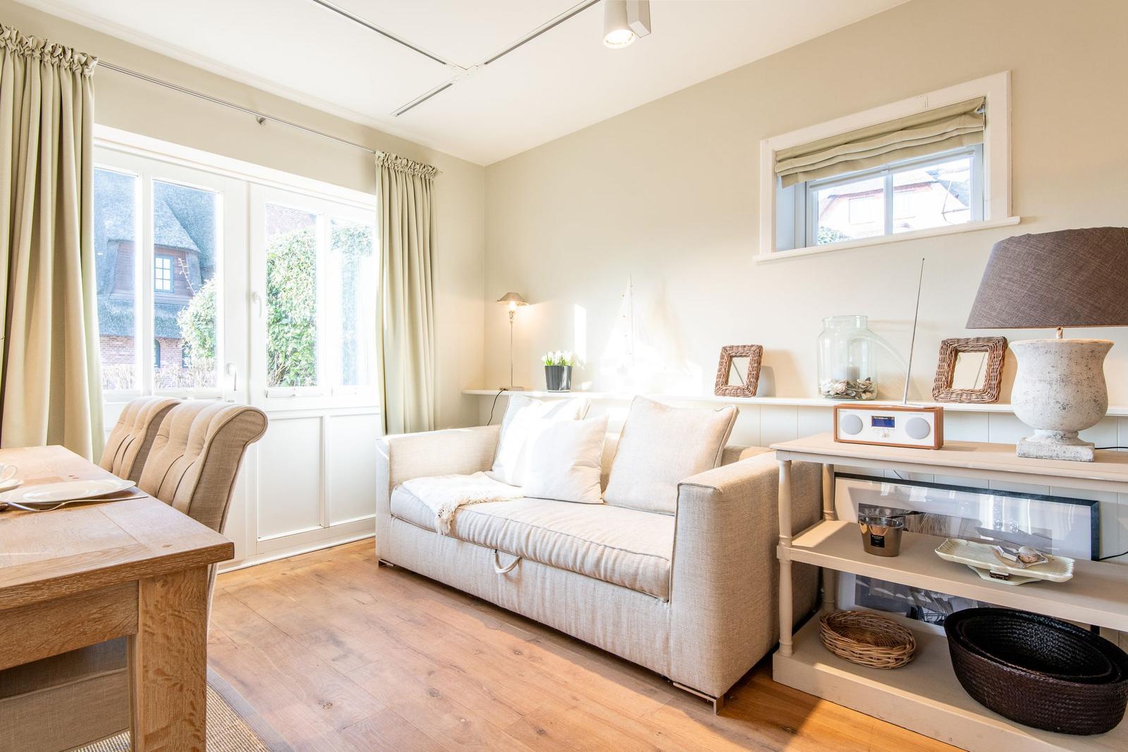 Wohn- und Essbereich mit Sofa, Tisch und Fenster.