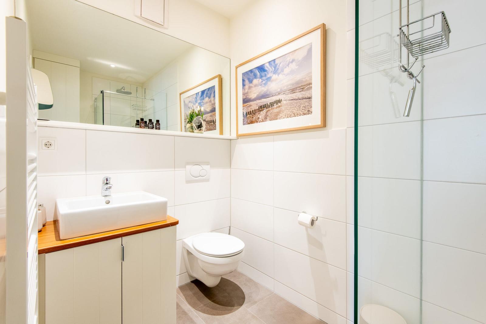 Badezimmer mit Dusche, Toilette und Waschbecken mit Spiegel