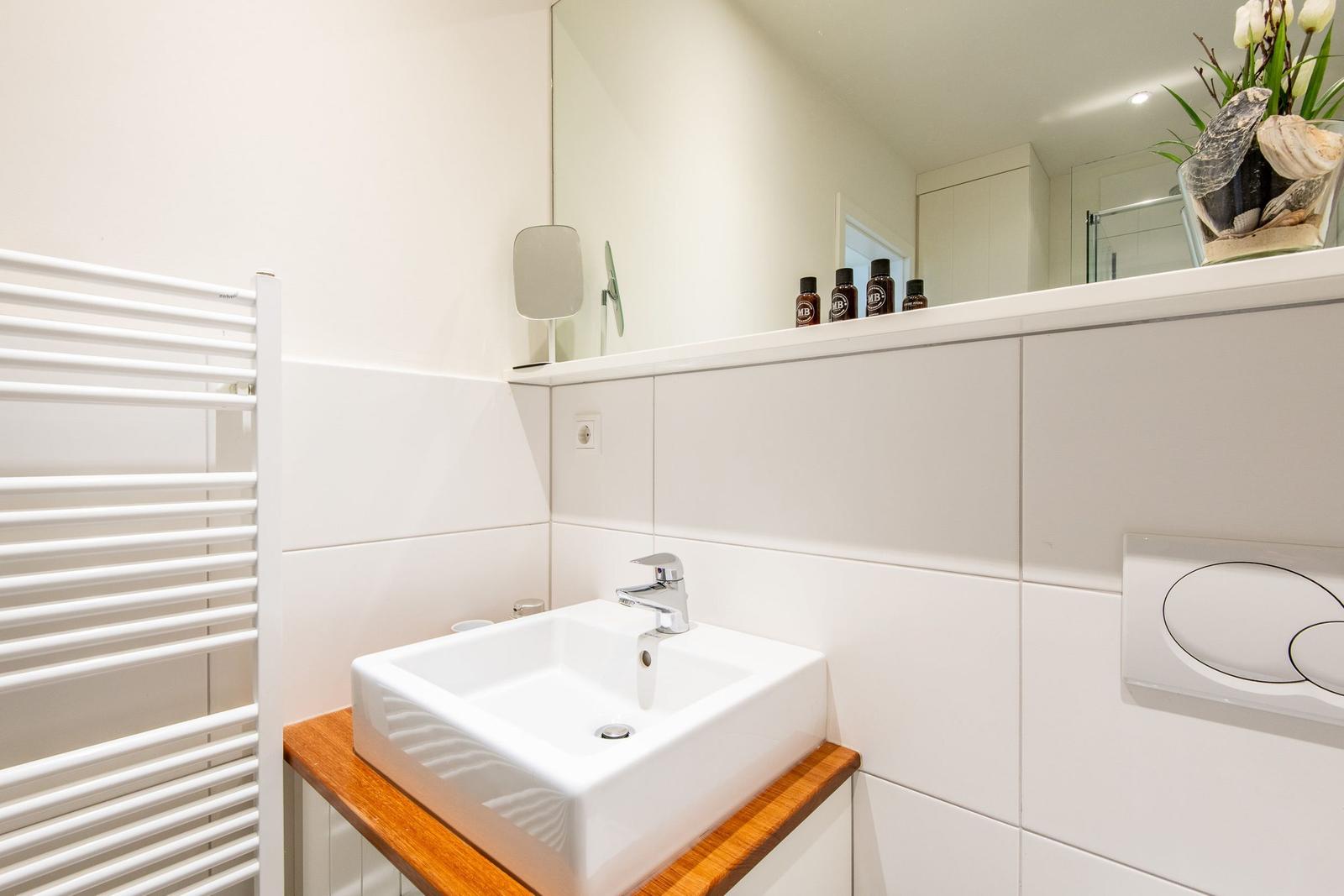 Badezimmer mit Waschbecken auf Holz, Spiegel und Heizkörper.