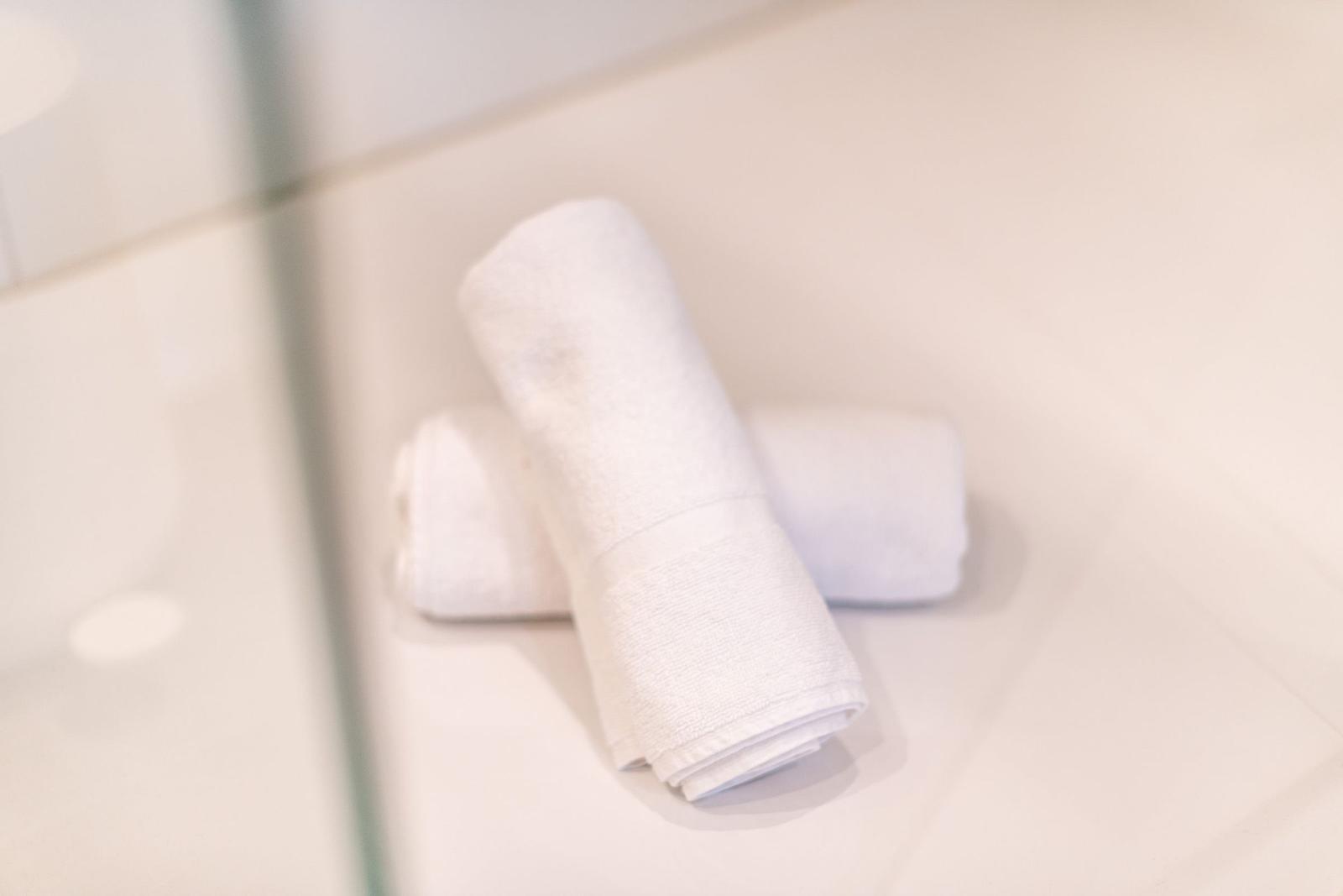 Zwei weiße Handtücher liegen auf einer hellen Fläche.