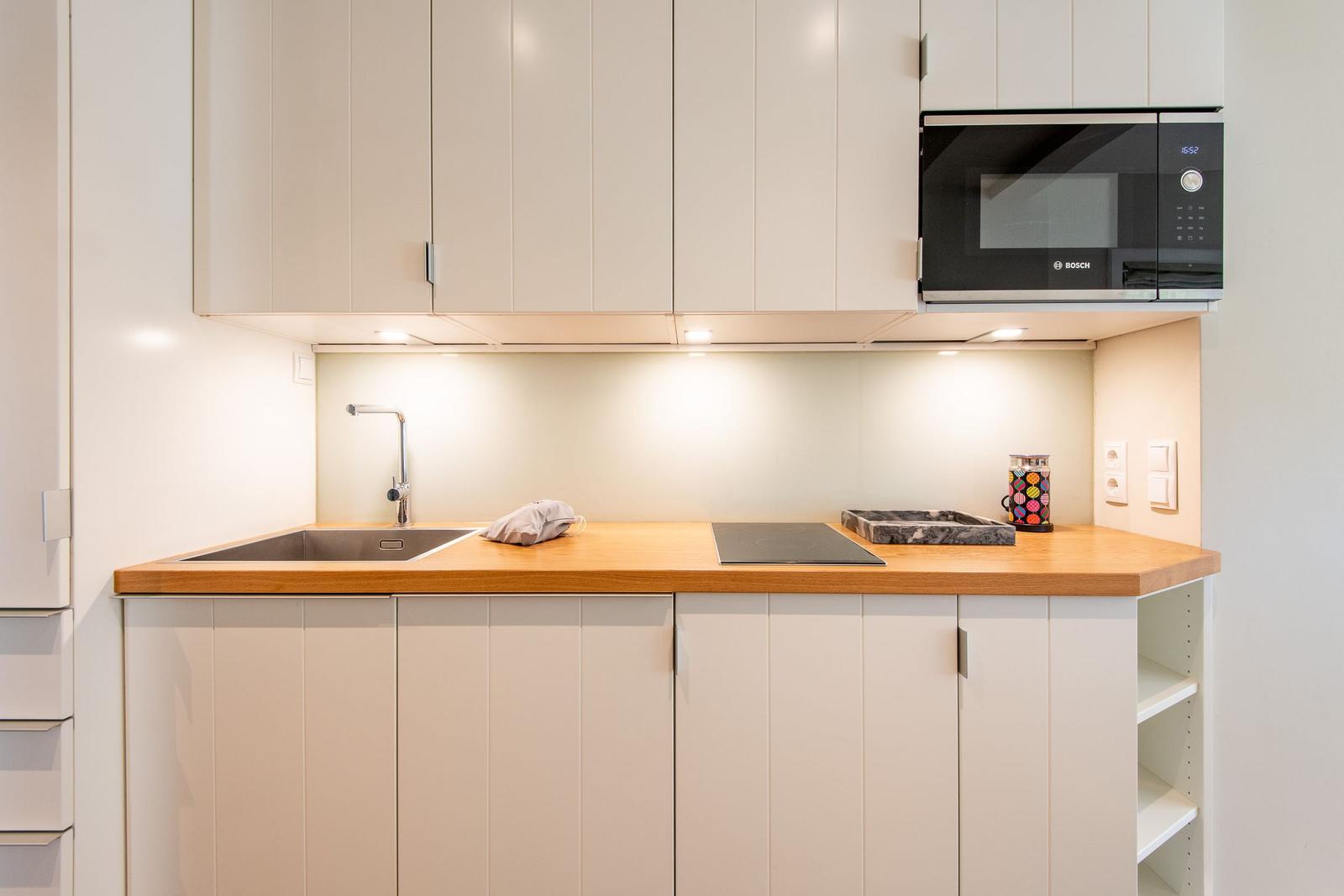 Küche mit Holzplatte, Spüle, Herd und Mikrowelle.