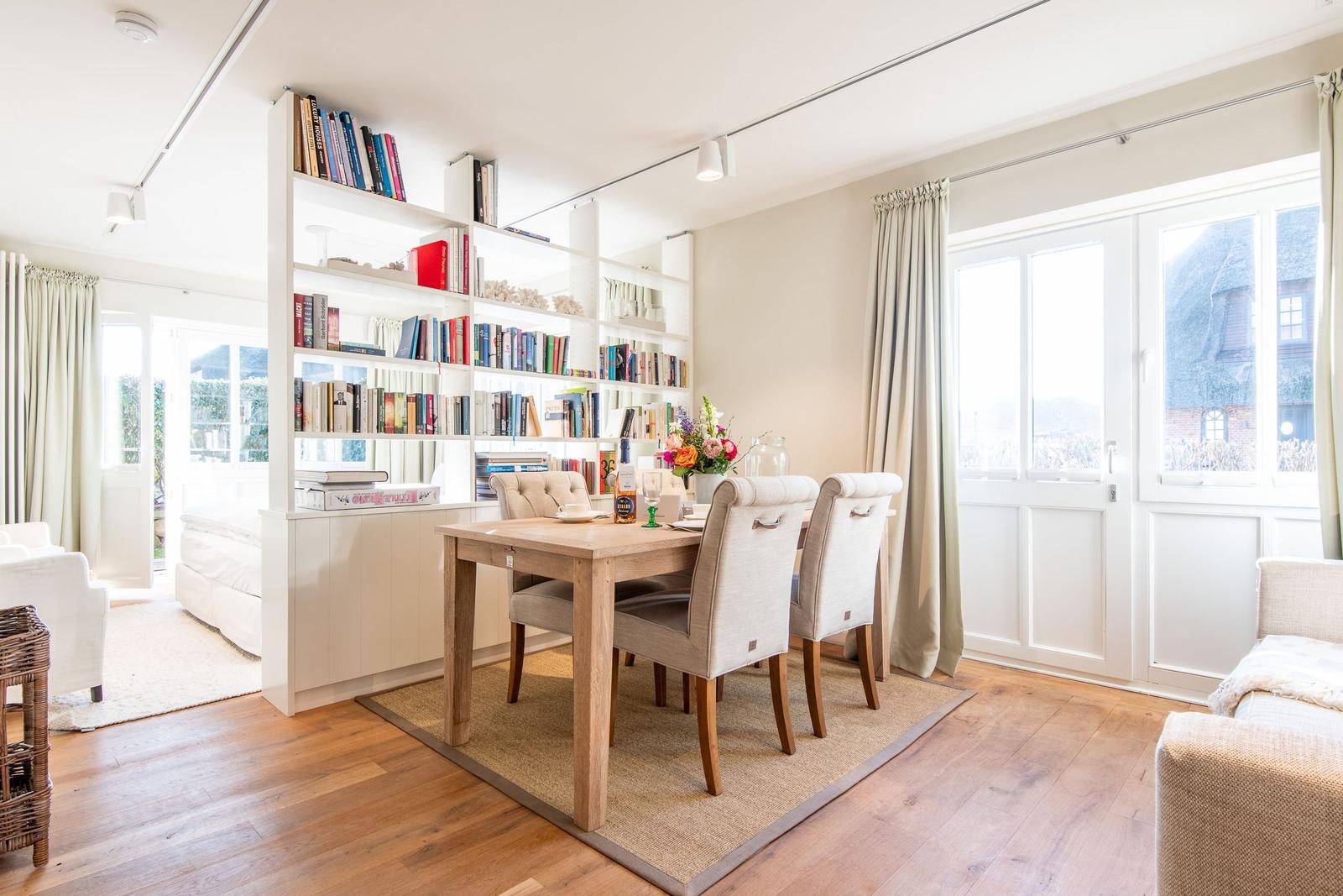 Essbereich mit Tisch, Stühlen und Bücherregal. Durchgang zur Schlafzimmerseite.