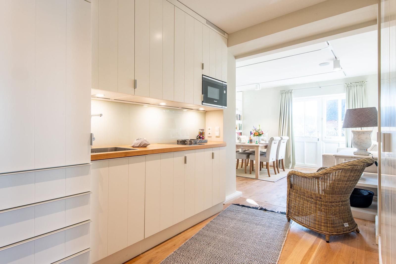 Küche mit Holzoberfläche und Mikrowelle. Blick in Esszimmer mit Tisch und Stühlen.