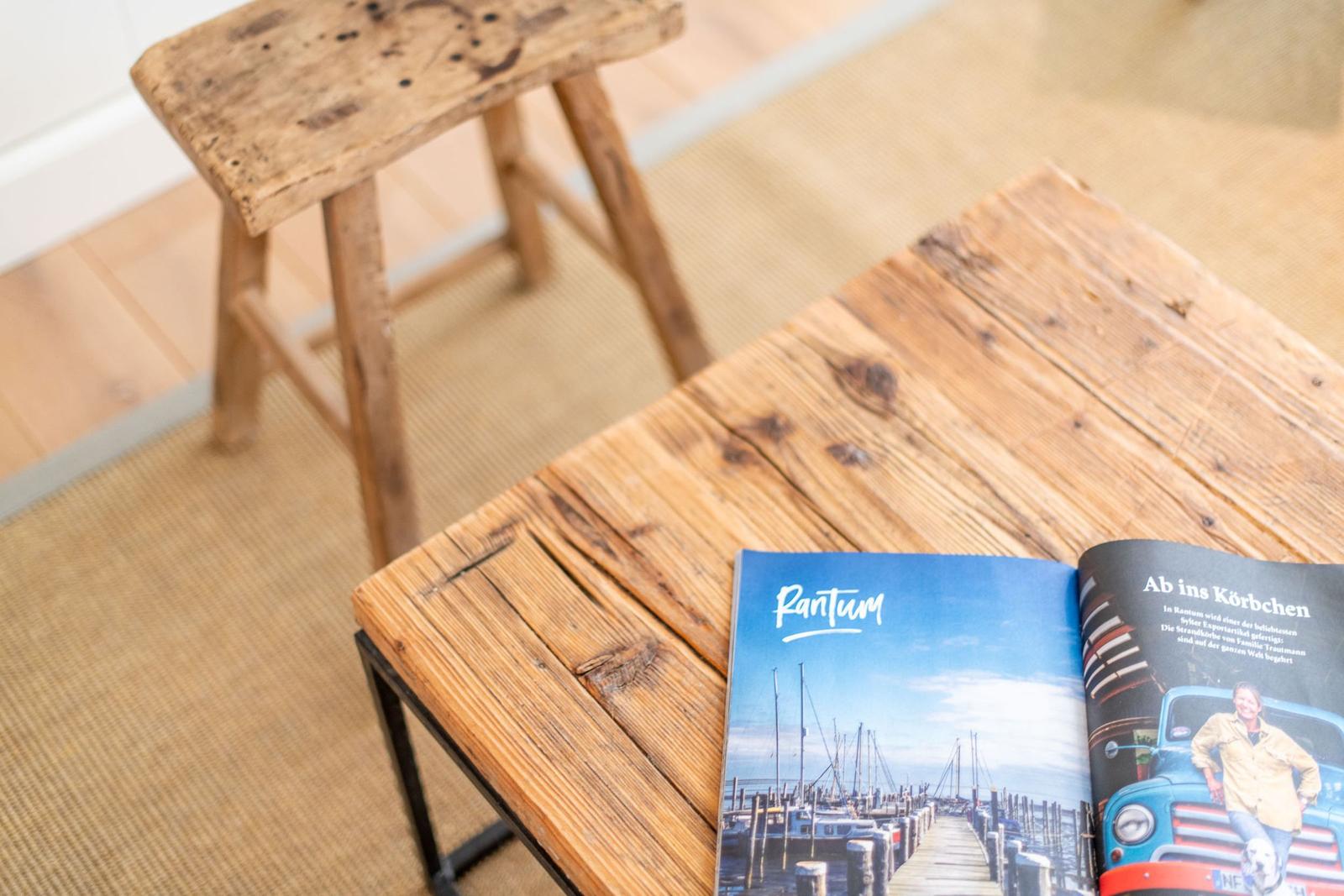 Holztisch mit Magazin und Hocker auf Teppichboden