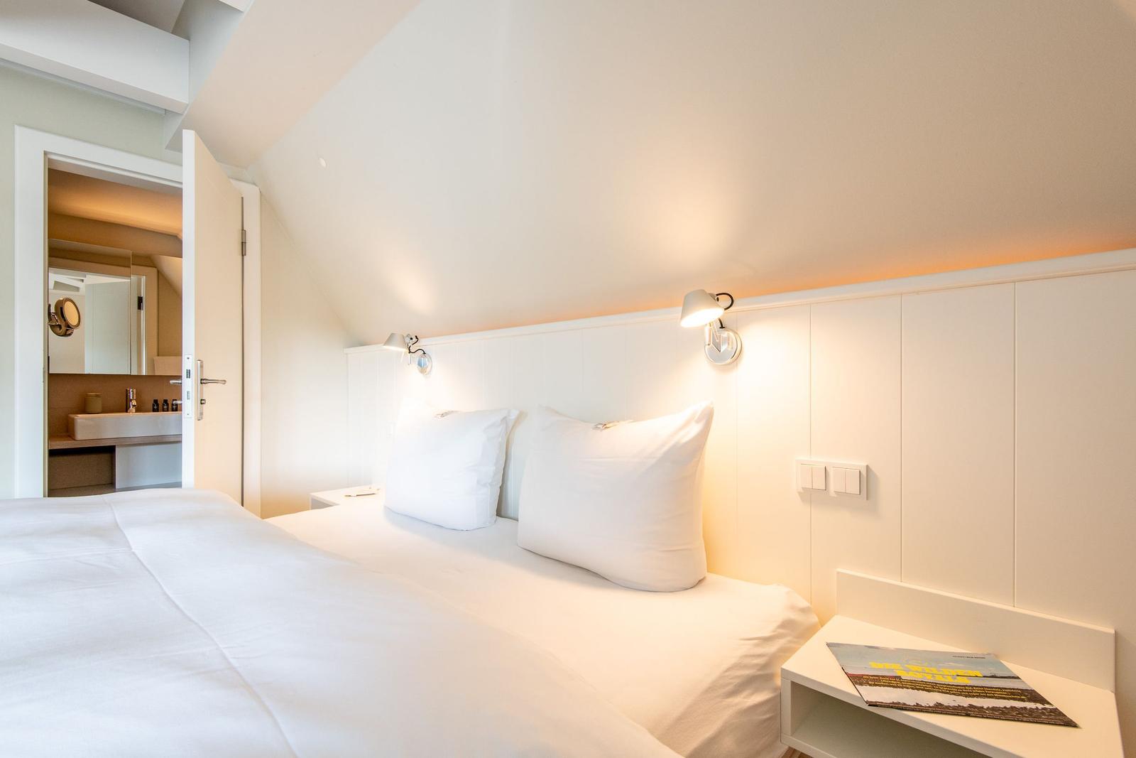 Schlafzimmer mit Doppelbett, Nachttisch und angrenzender Toilette.