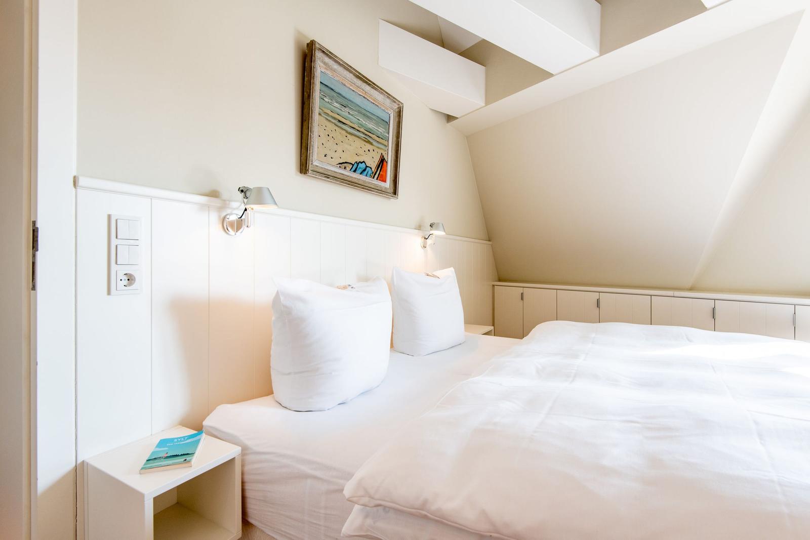 Schlafzimmer mit Doppelbett, Nachttisch und Wandbild