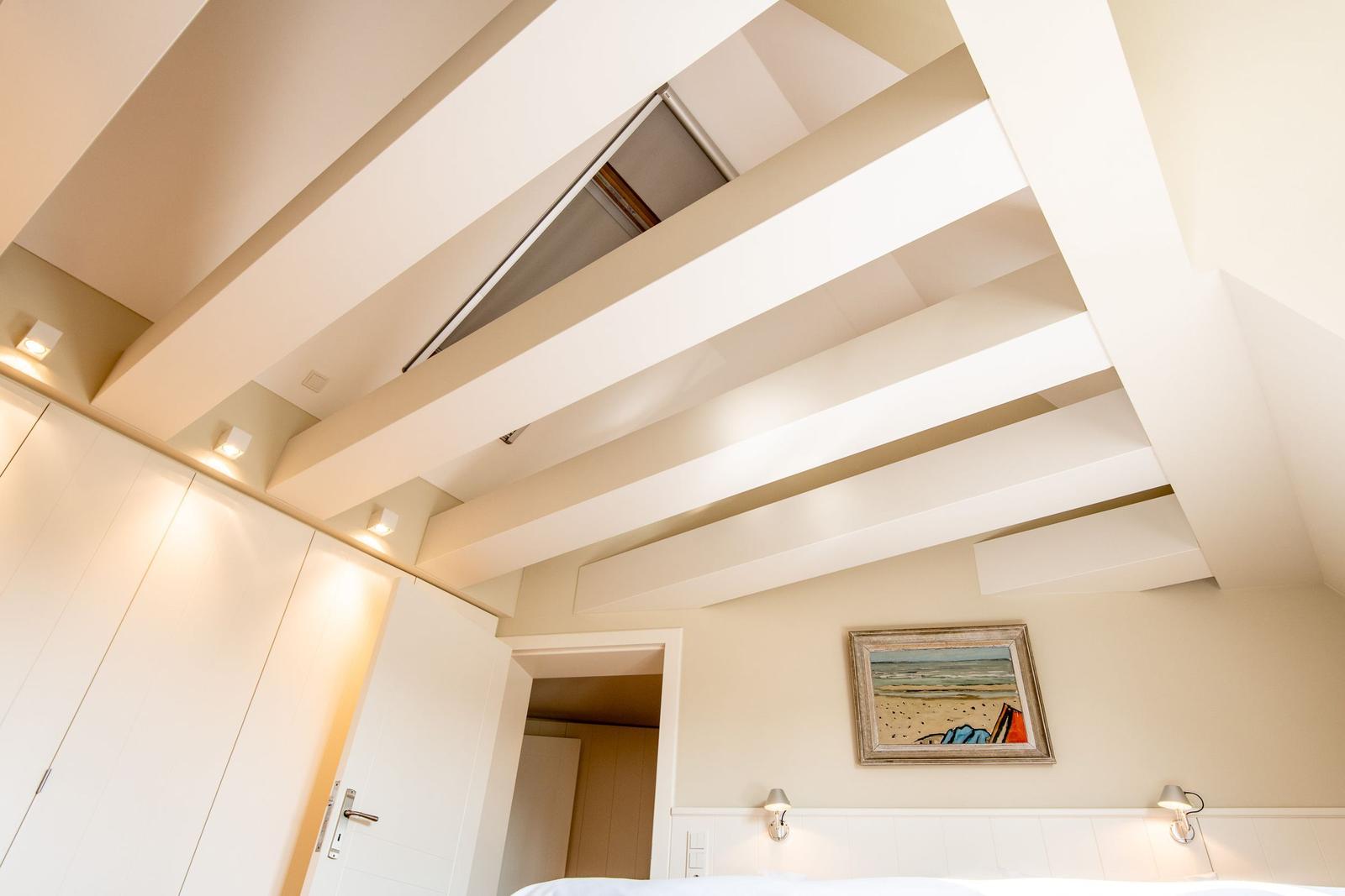 Schlafzimmer mit weißen Balken an der Decke und einem Bild an der Wand.