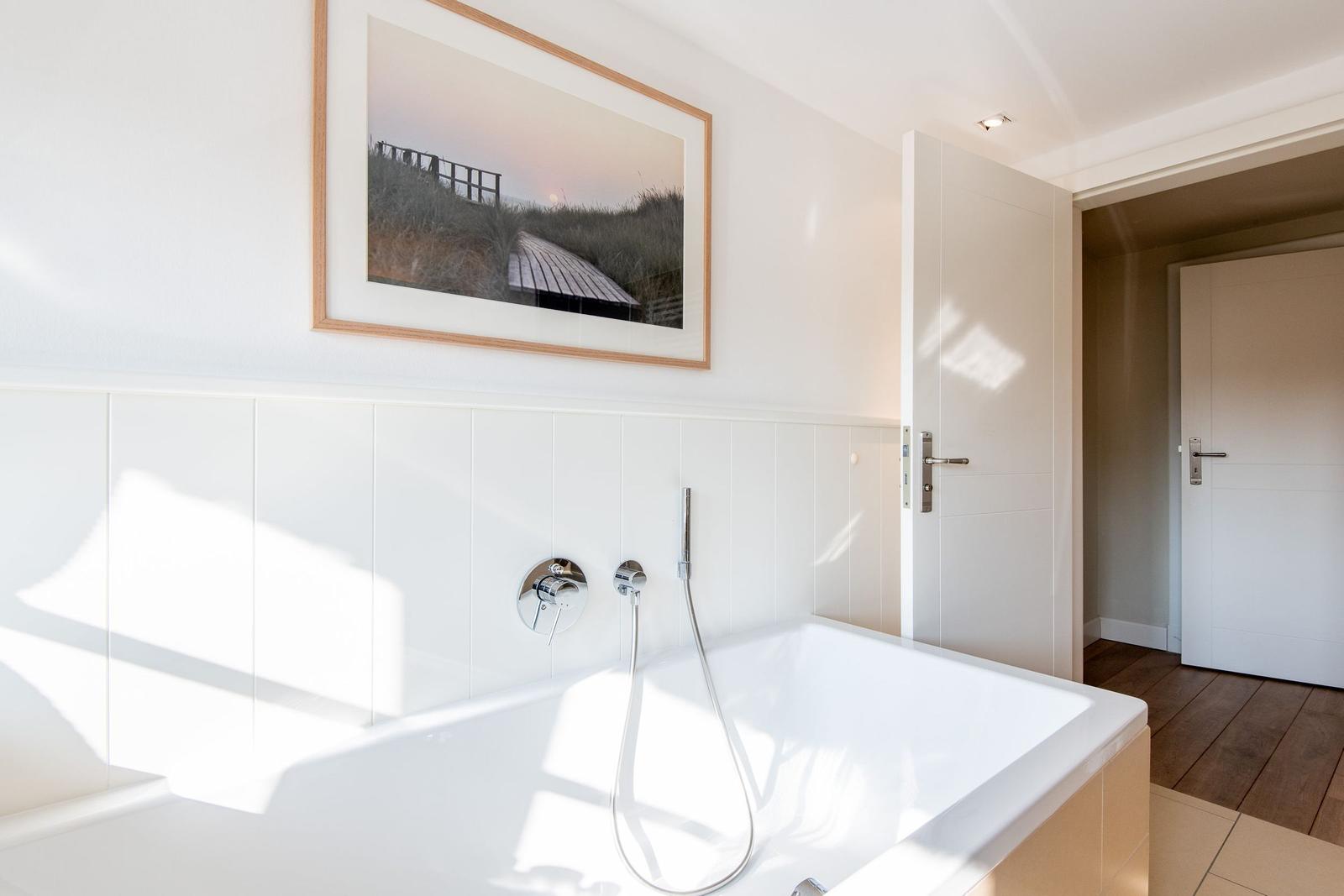 Badezimmer mit Whirlpool, Wandbild und Holzboden im Flur.