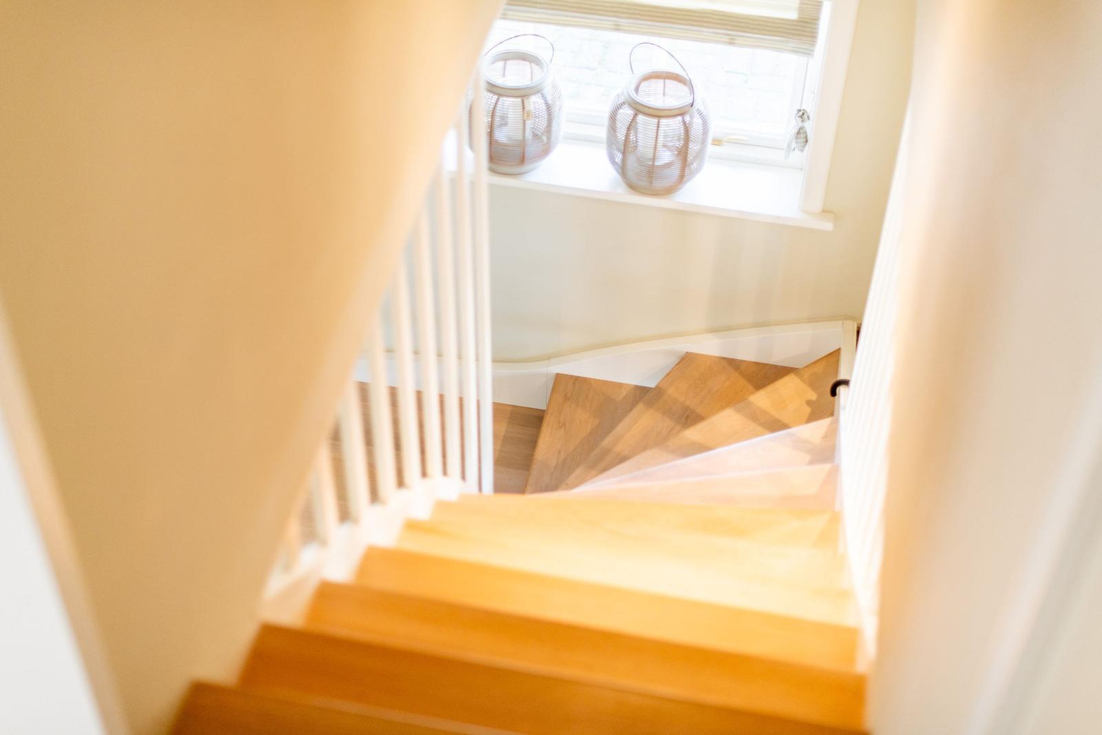 Holzstufen führen nach oben. Fenster mit zwei weißen Laterne.