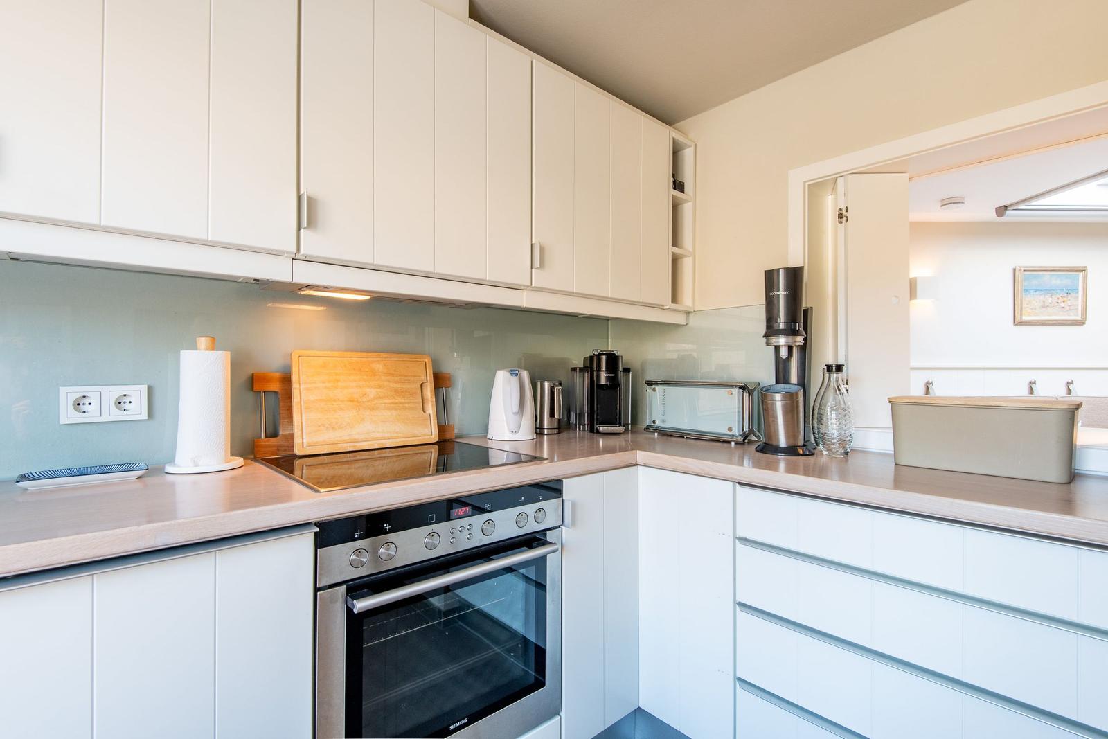 Moderne Küche mit weißen Schränken, Edelstahlherd und Arbeitsplatte.