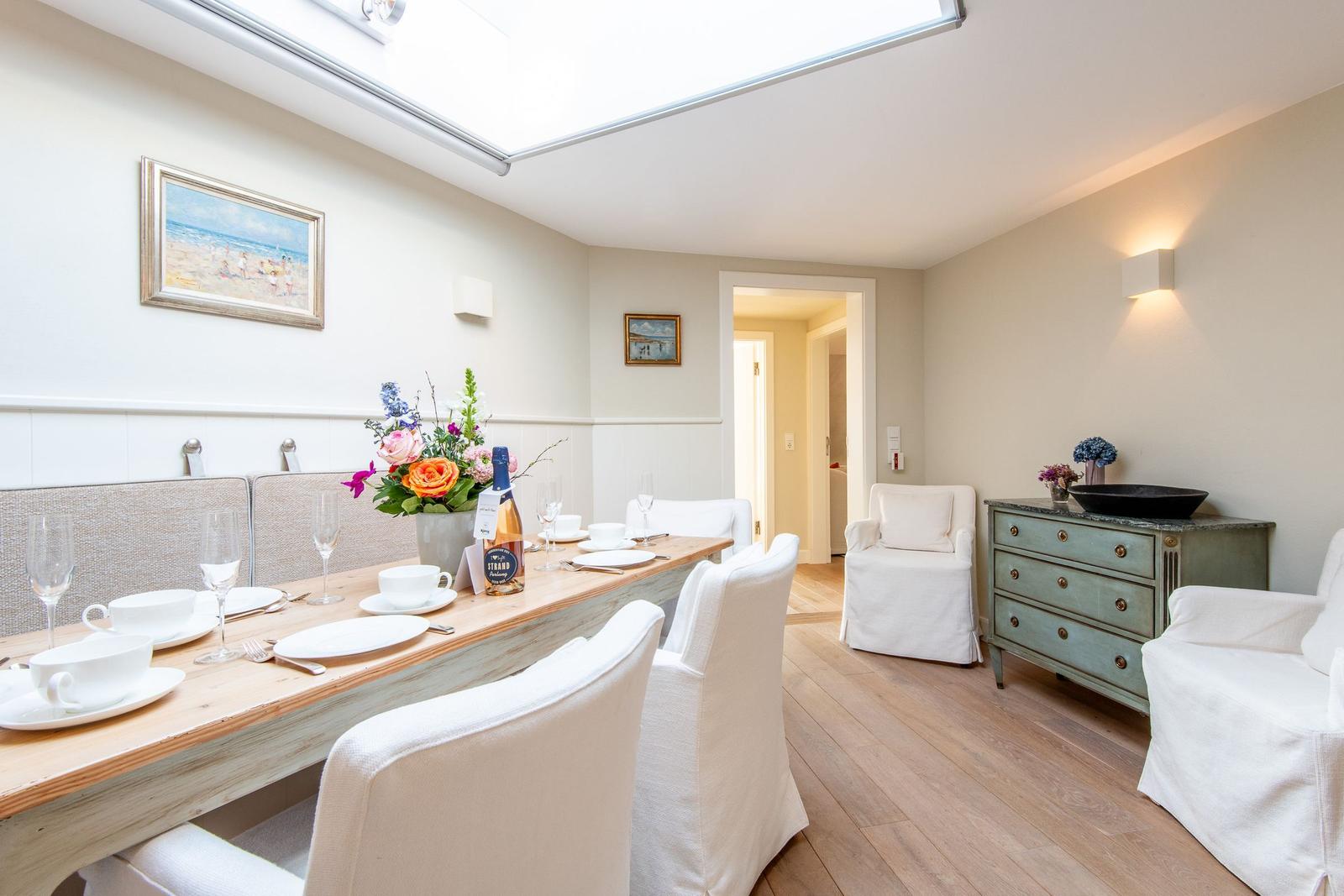 Esszimmer mit Tisch, Stühlen und Deckenfenster. Hintergrund: Flur und Schrank.