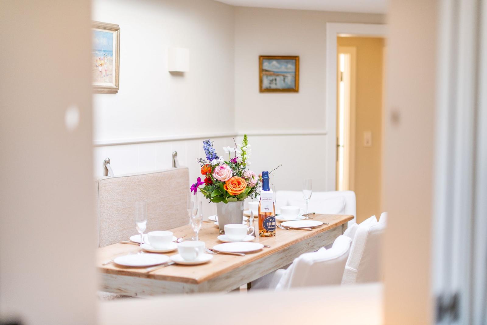 Esstisch mit Platz für sechs Personen, Blumen und Flasche auf dem Tisch.