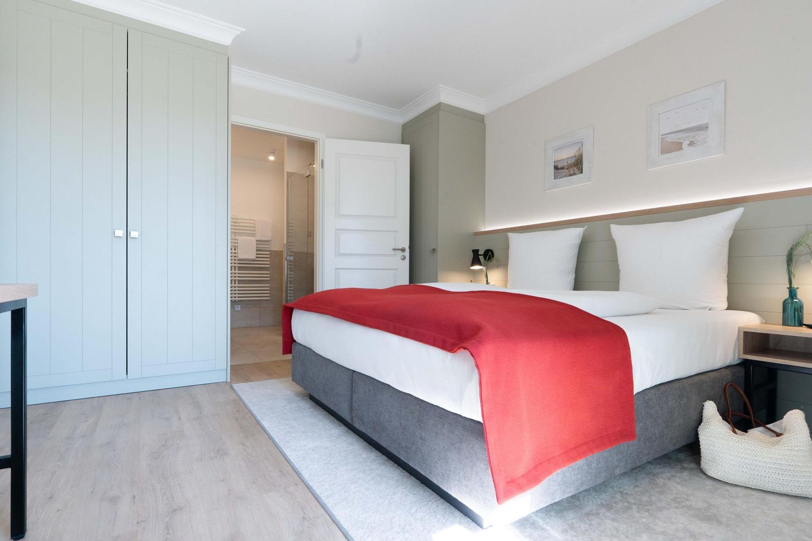 Schlafzimmer mit Doppelbett, Kleiderschrank und angrenzender Dusche.