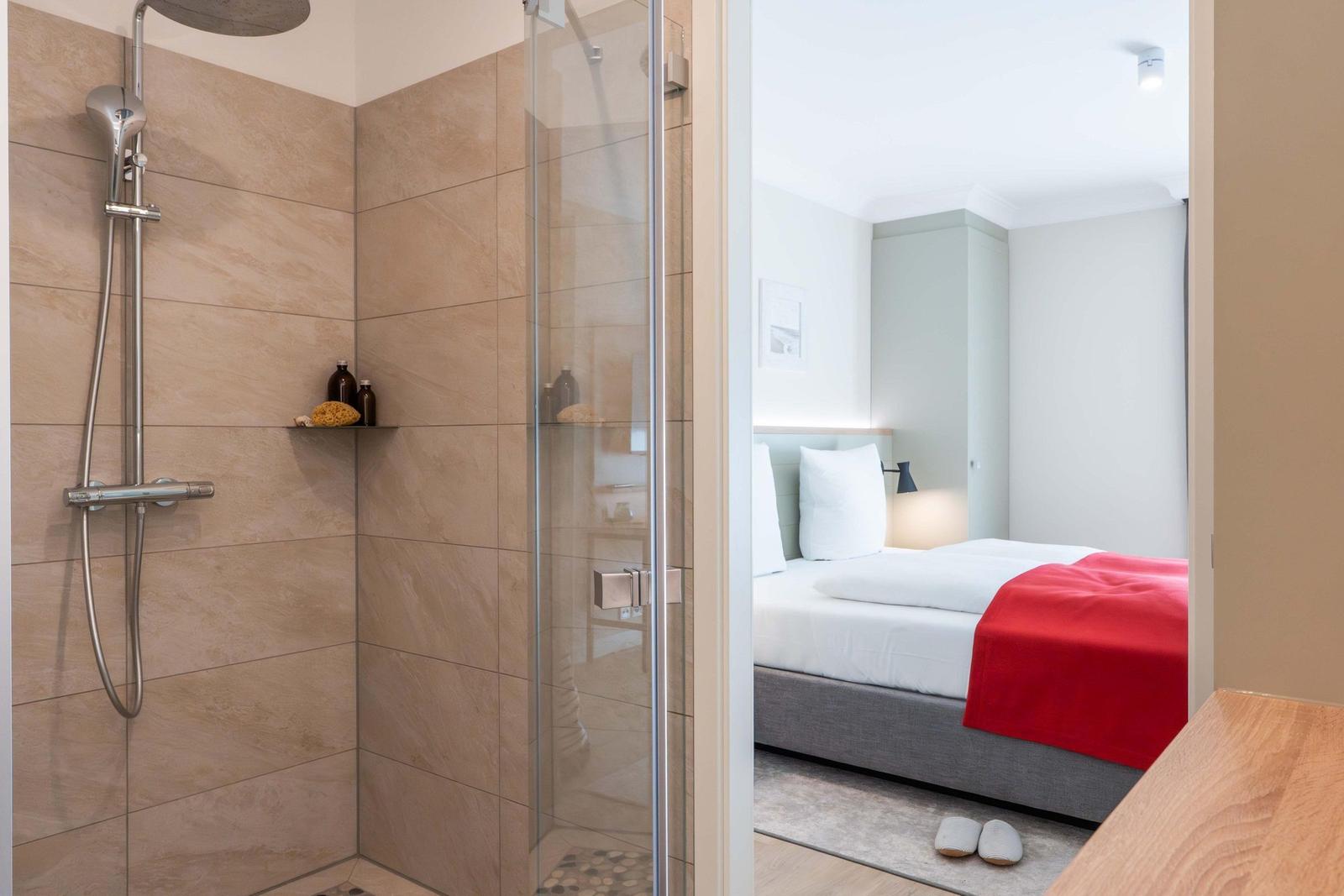 Dusche mit Glaswand und Badewanne im Hintergrund