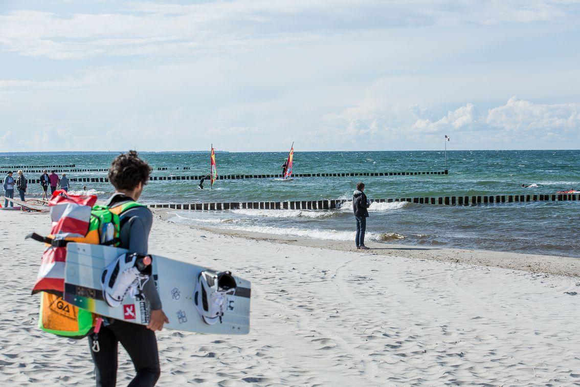 Ein Strand mit Surfern und einem Holzverbau im Meer.