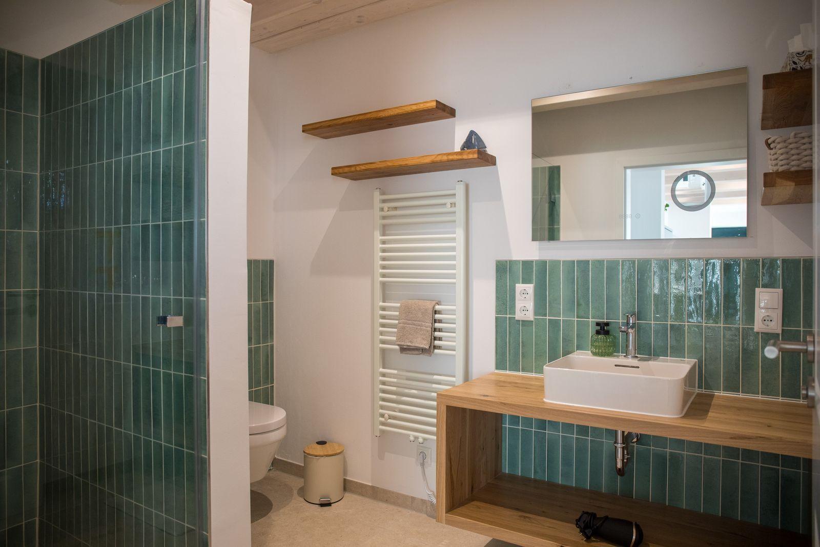 Badezimmer mit Dusche, Waschbecken und Heizkörper