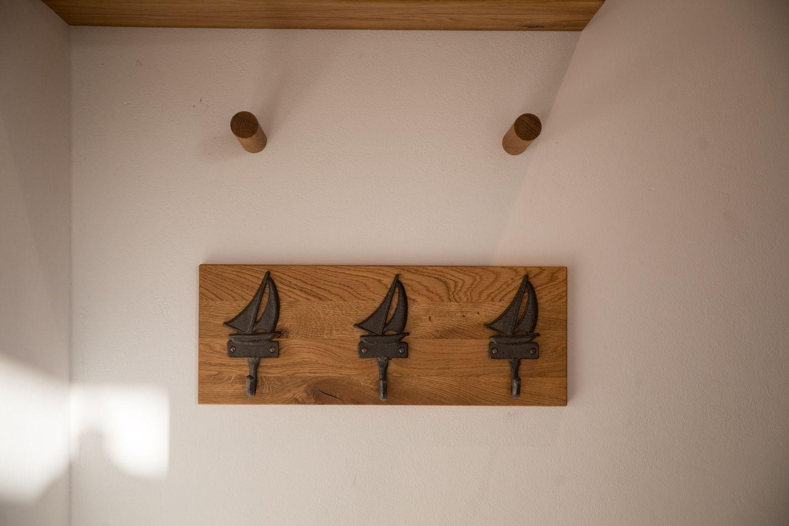 Holzpaneel mit drei Segelyachten-Haken an der Wand