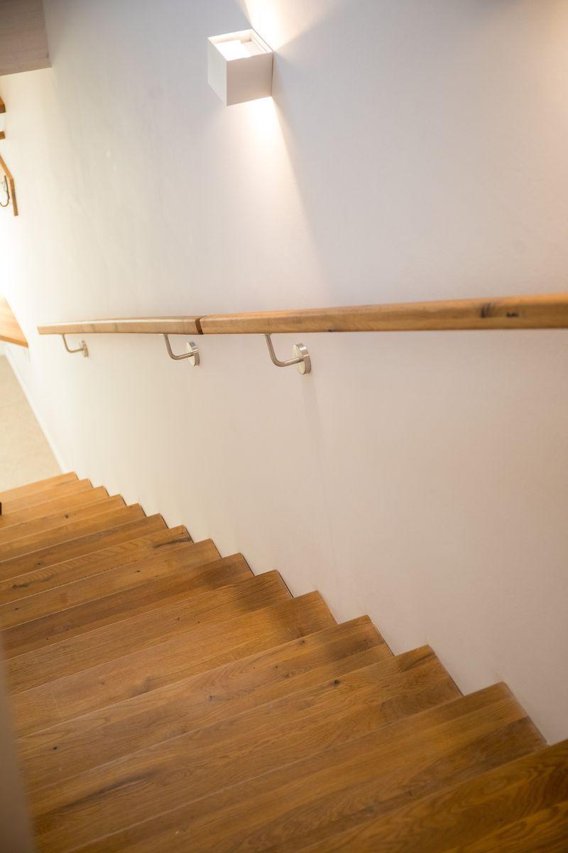 Holzgetäfelte Treppe mit Handlauf und Wandlampe.