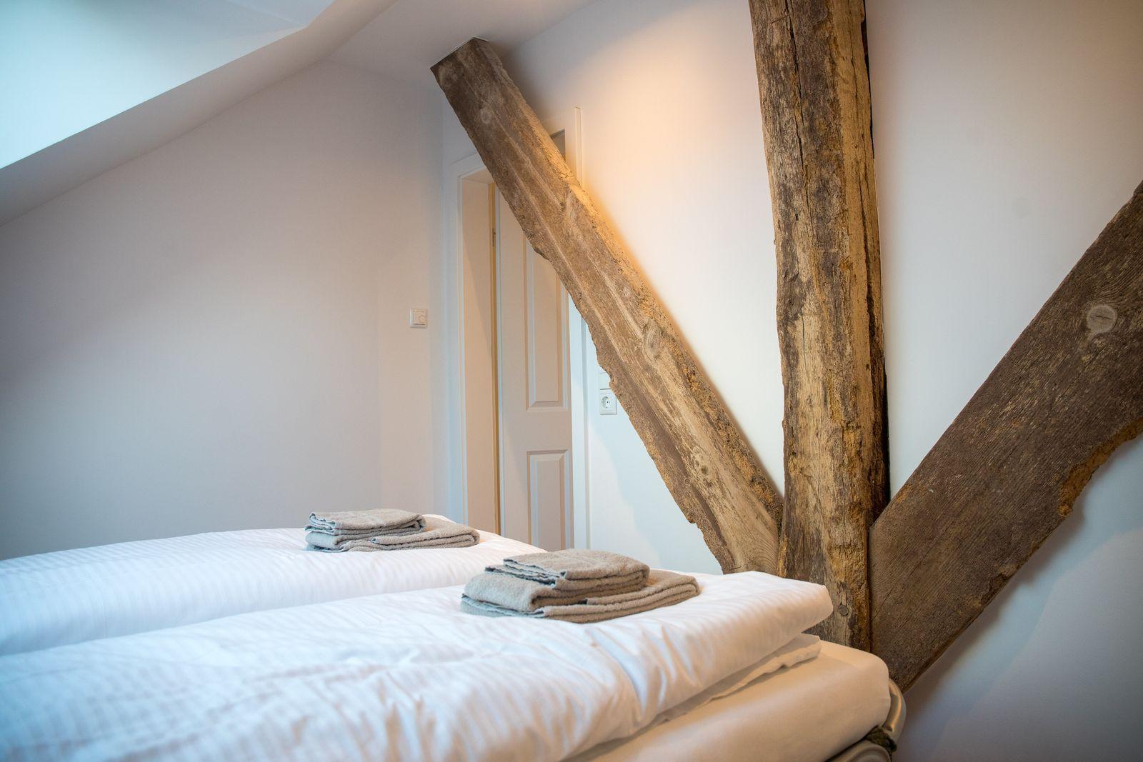Zimmer mit zwei Betten und rustikalen Holzbalken an der Wand.
