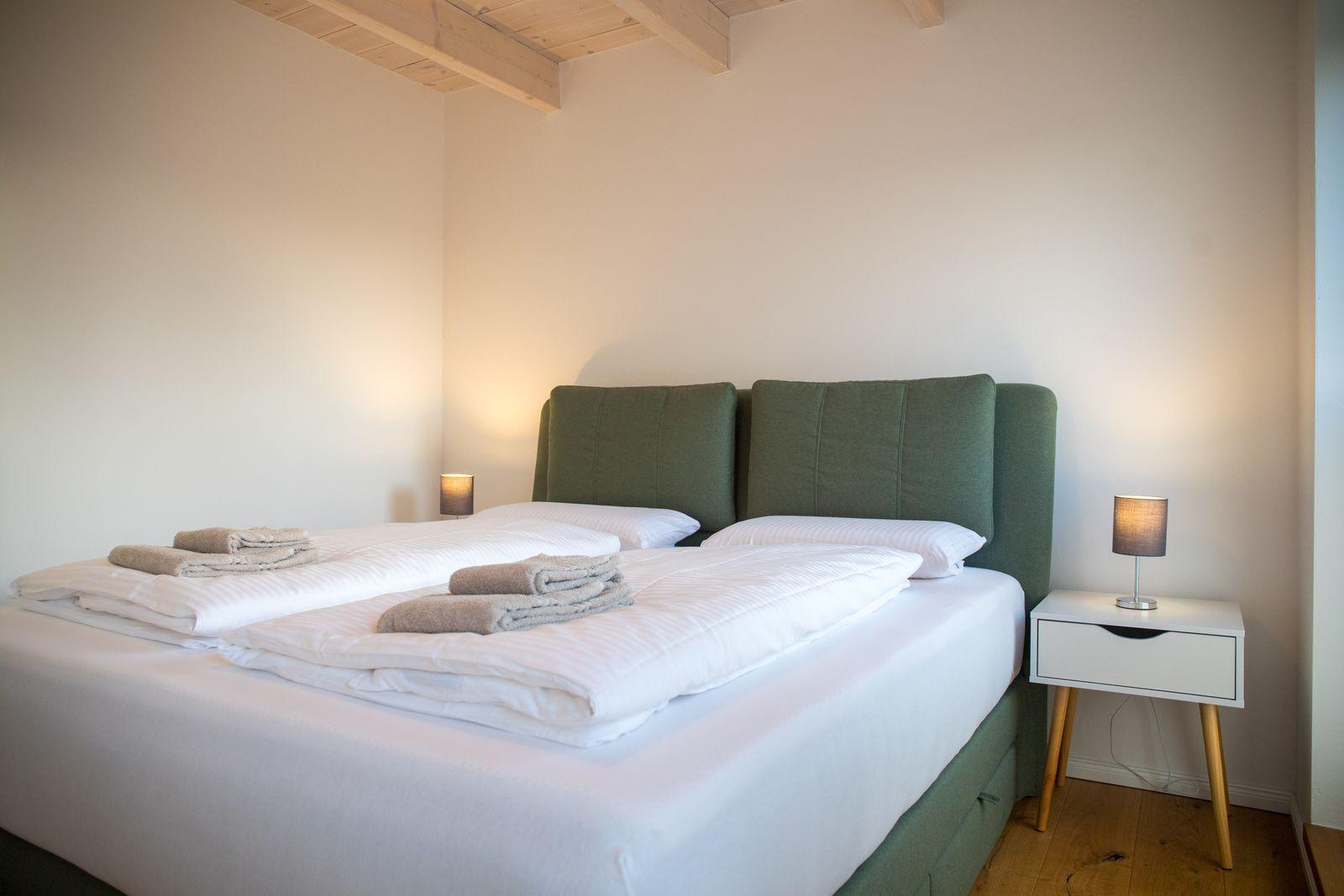 Schlafzimmer mit Bett, Nachttisch und Holzdecke.