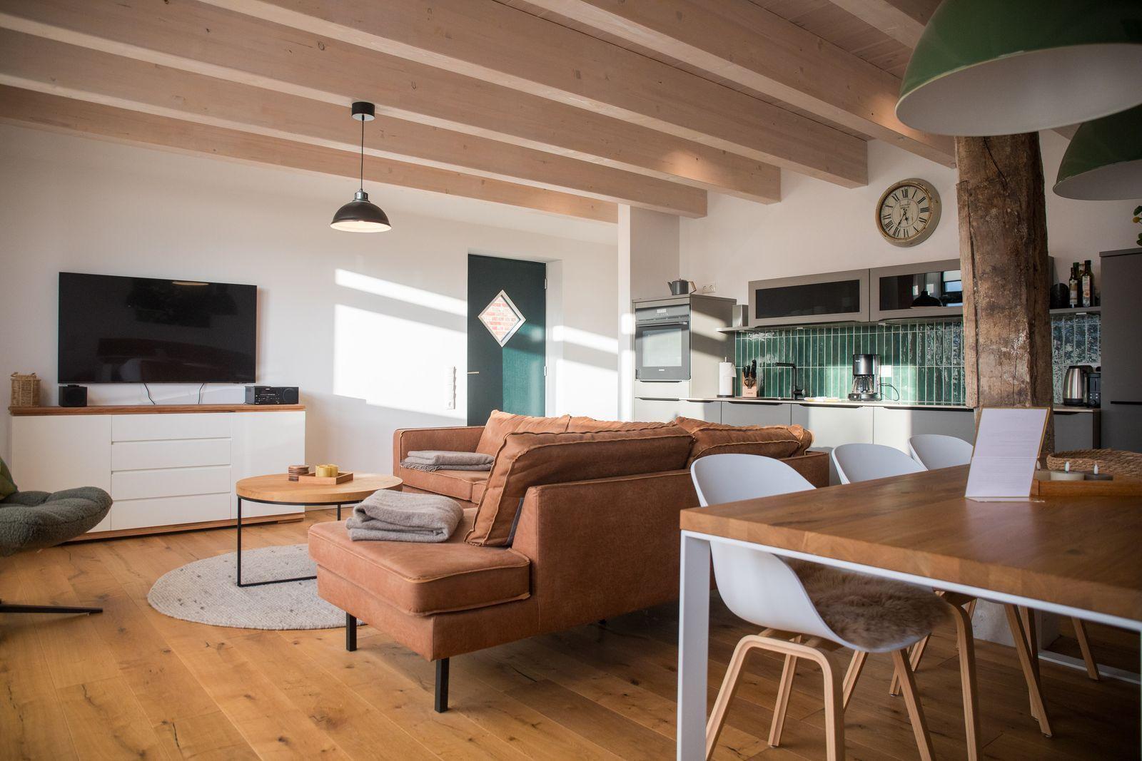 Wohn- und Essbereich mit Holzdecke, Sofa und Esstisch.