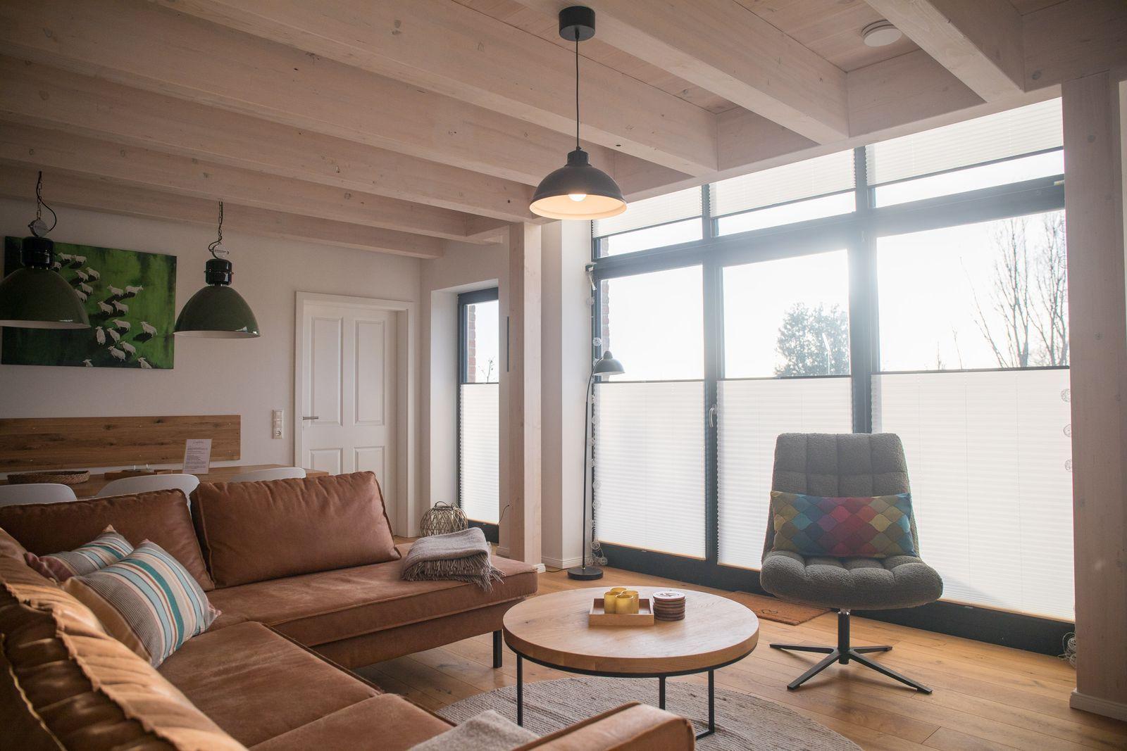 Wohnzimmer mit braunem Sofa, runden Tisch und großem Fenster.