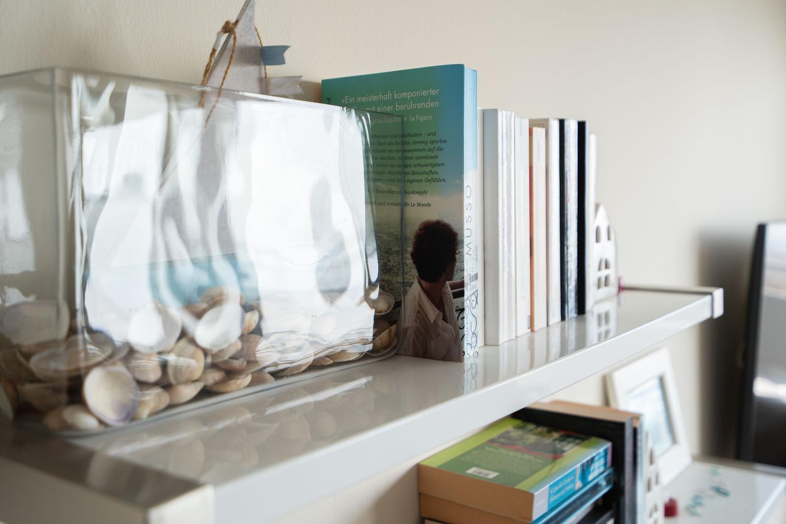 Regal mit Büchern und Glasbehälter mit Steinen.