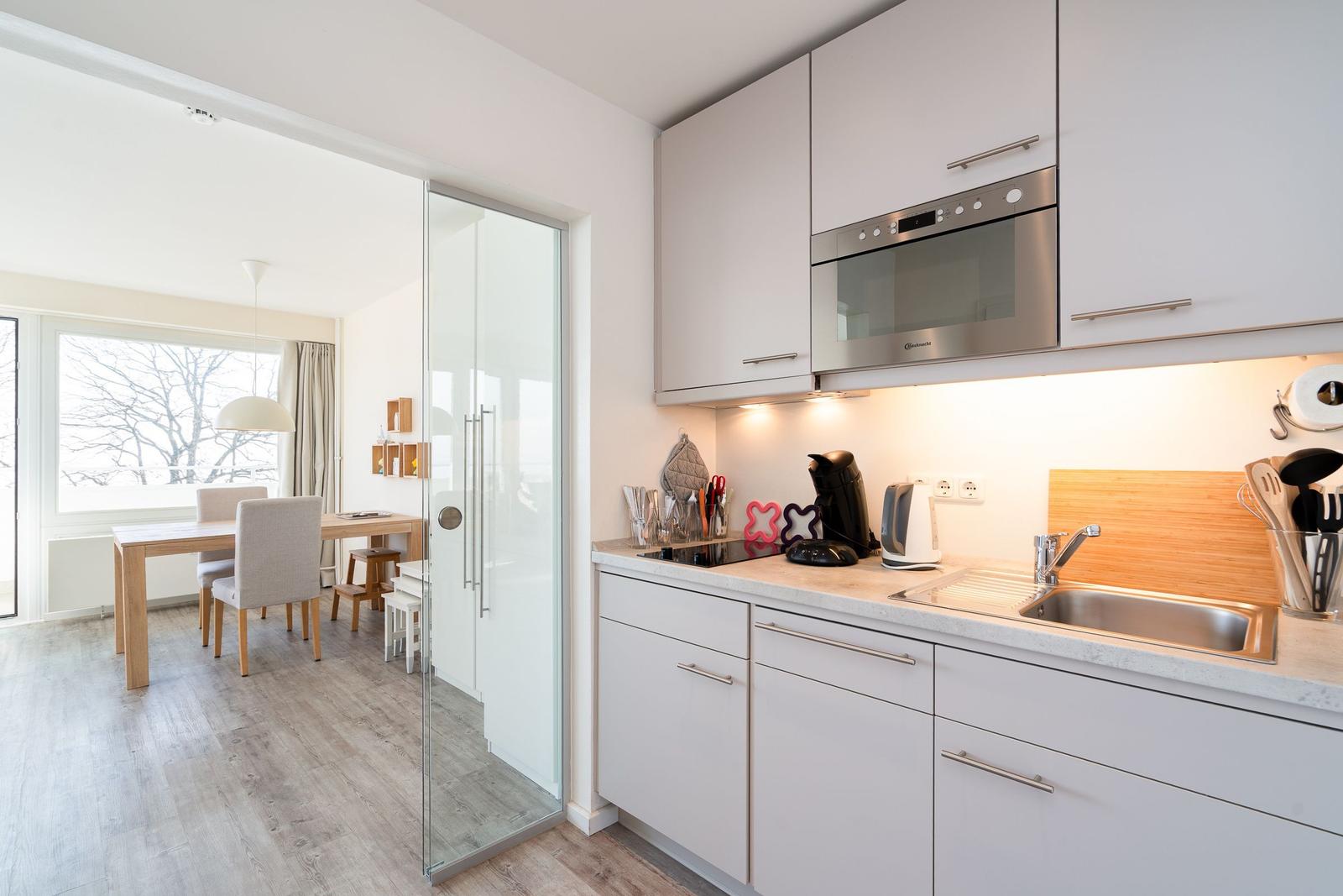 Küche mit Arbeitsplatte, Spüle und Glaswand zur Essnische.