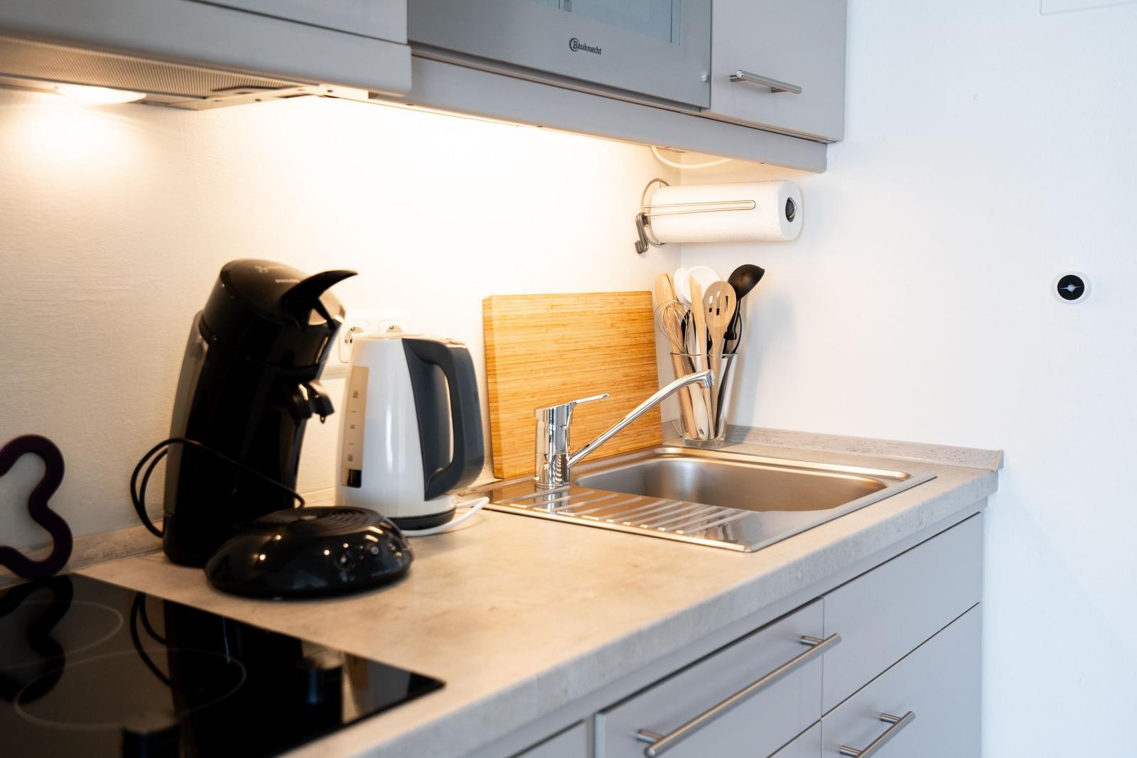 Küche mit Spüle, Kaffeemaschine und Wasserkocher.