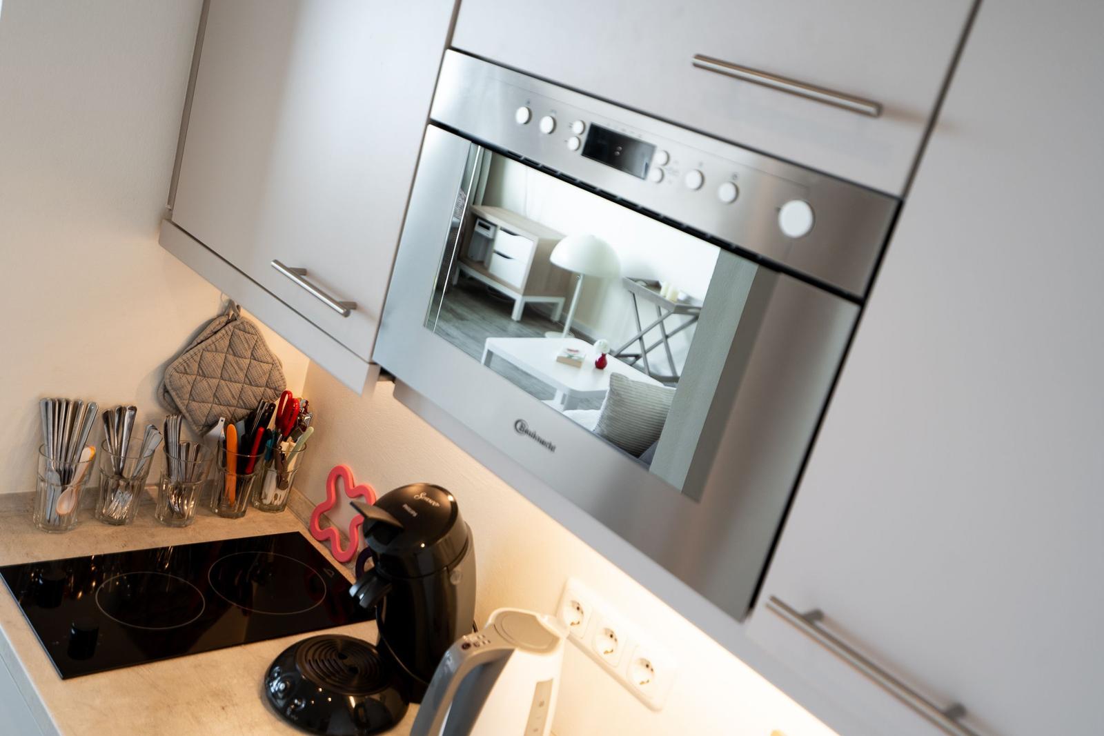 Küche mit Dunstabzugshaube, Kochfeld und Küchenzeile