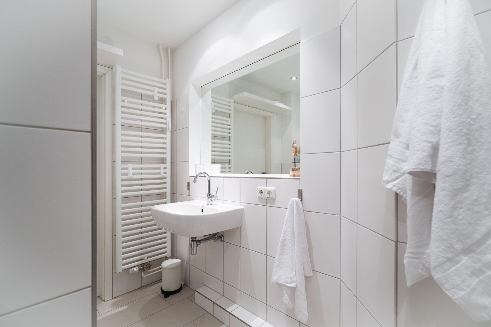 Badezimmer mit Spiegel, Waschbecken und Handtuch