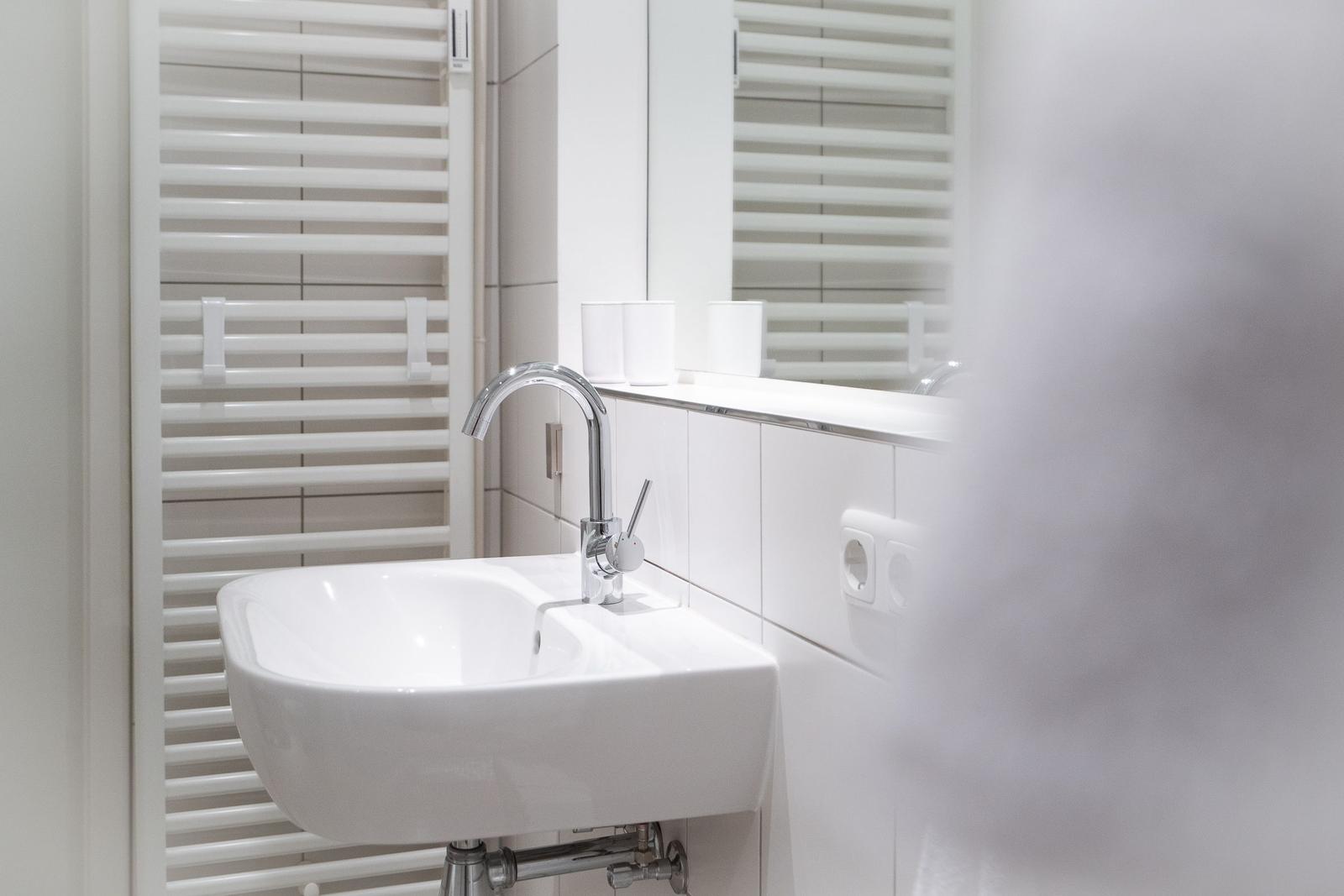 Bad mit Waschbecken, Spiegel und Heizkörper.