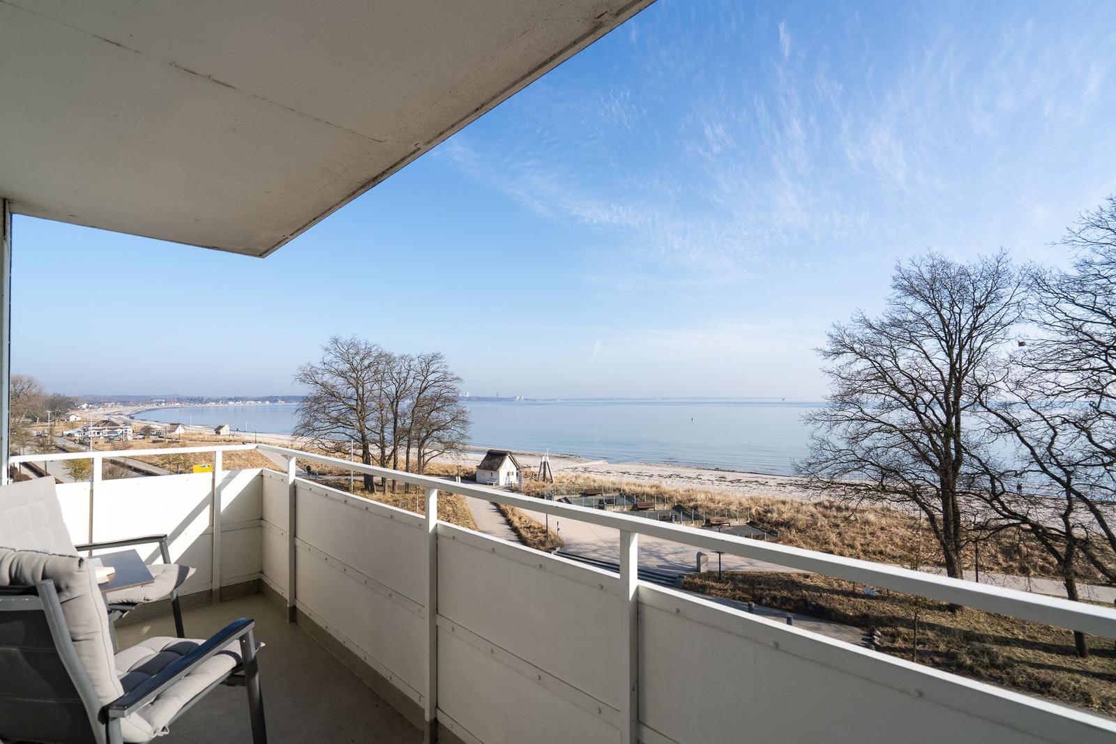 Balkon mit Sitzgelegenheit und Blick auf Strand und Meer.