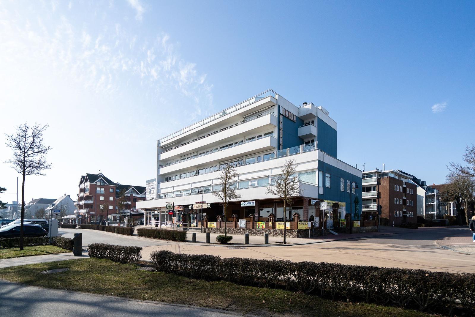 Moderne mehrstöckige Wohnanlage mit Balkonen und Geschäften im Erdgeschoss.