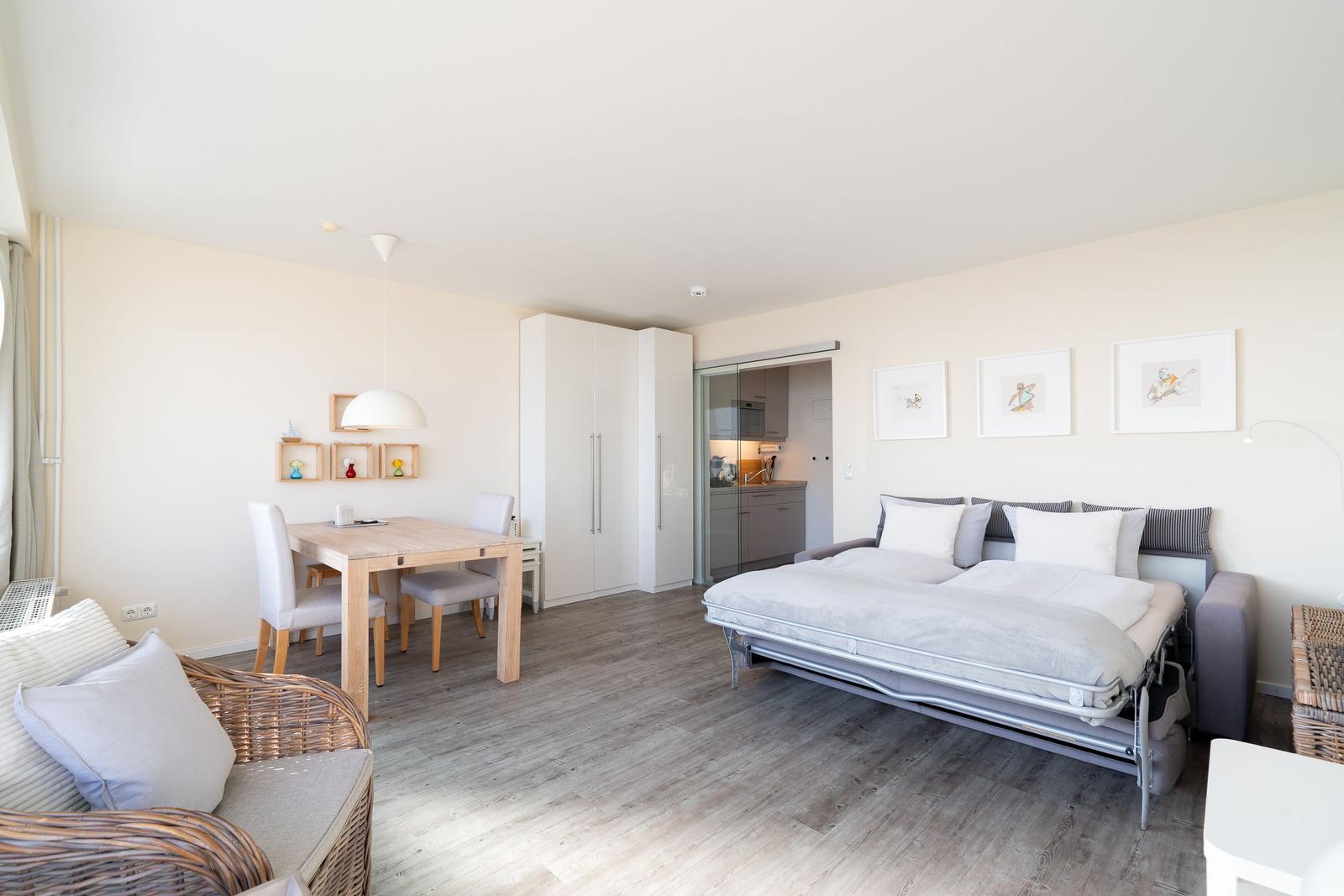 Wohnraum mit Schlafgelegenheit, Esstisch und Küchenbereich.