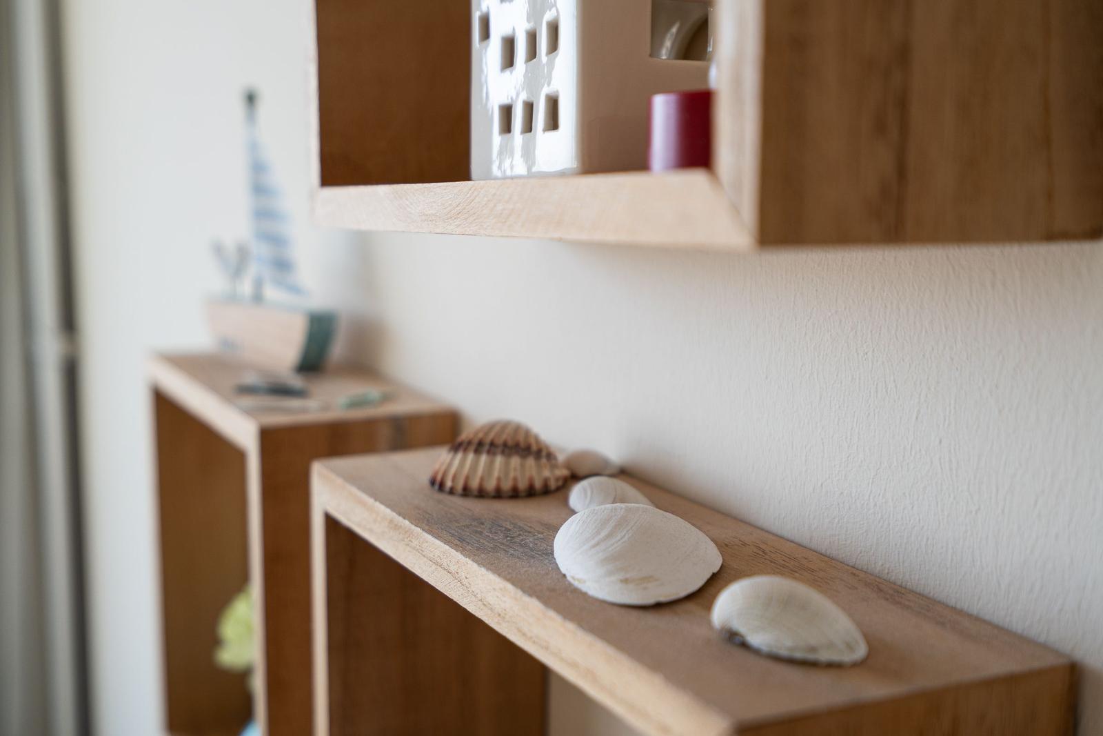 Holzregale mit Muscheln und Dekorationsgegenständen an der Wand
