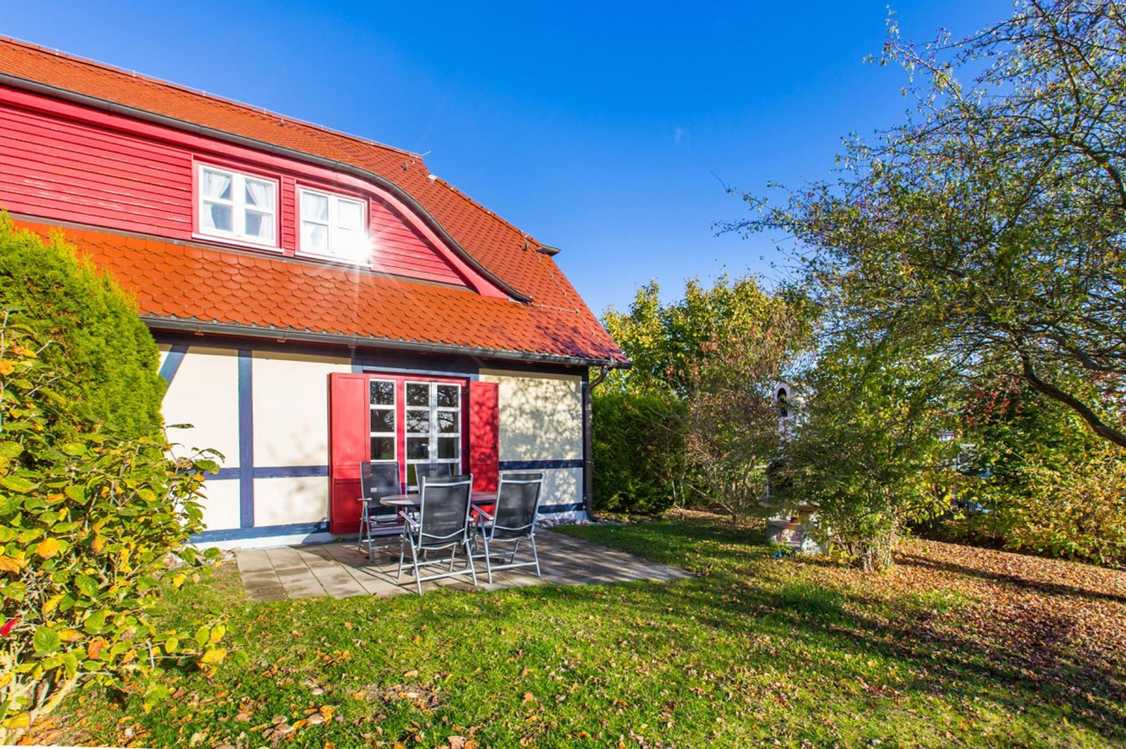 Rotes Haus mit Terrasse und Garten. Rote Fensterläden und Türen.