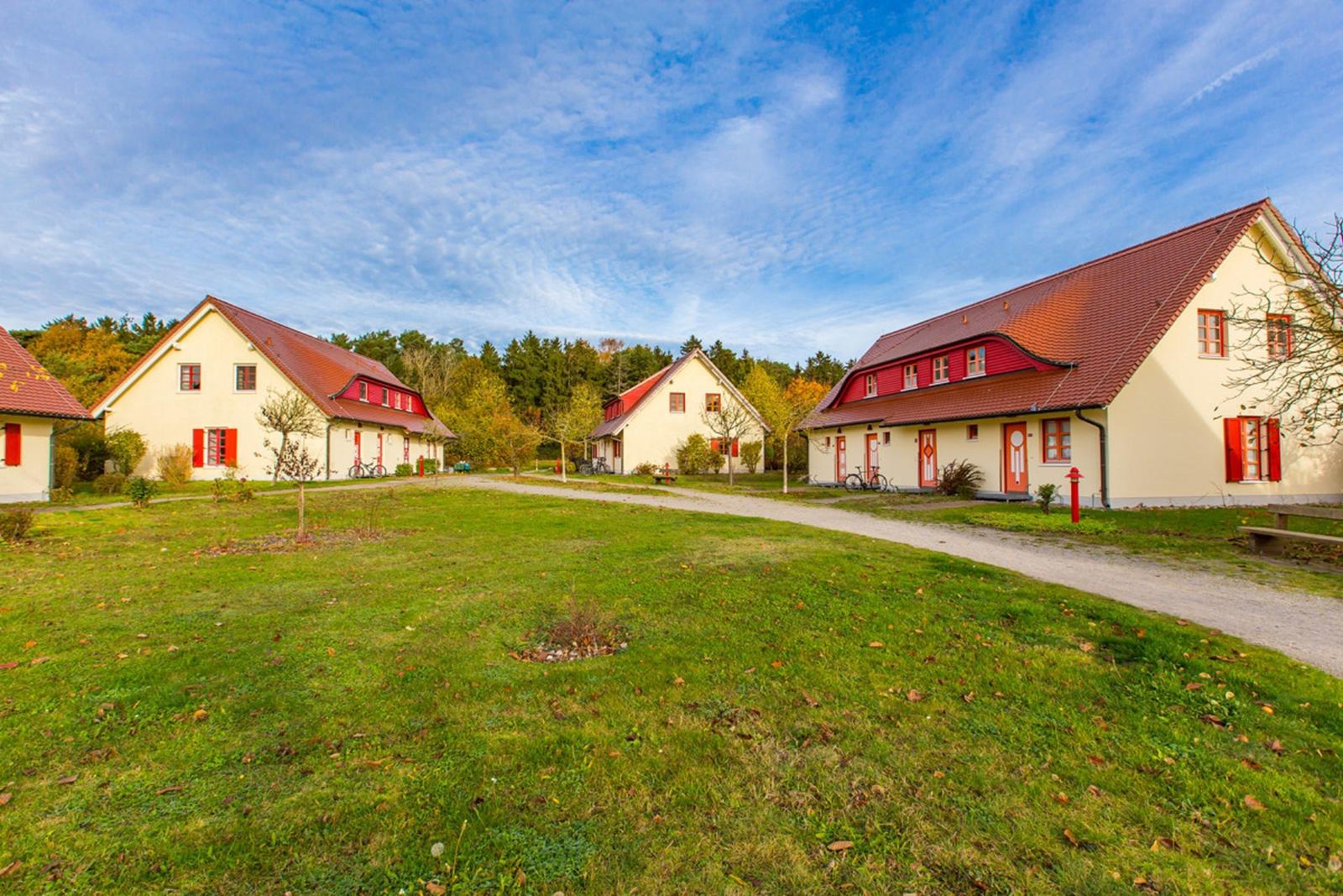 Häuser mit roten Dächern und Fensterläden stehen in einer grünen Umgebung.